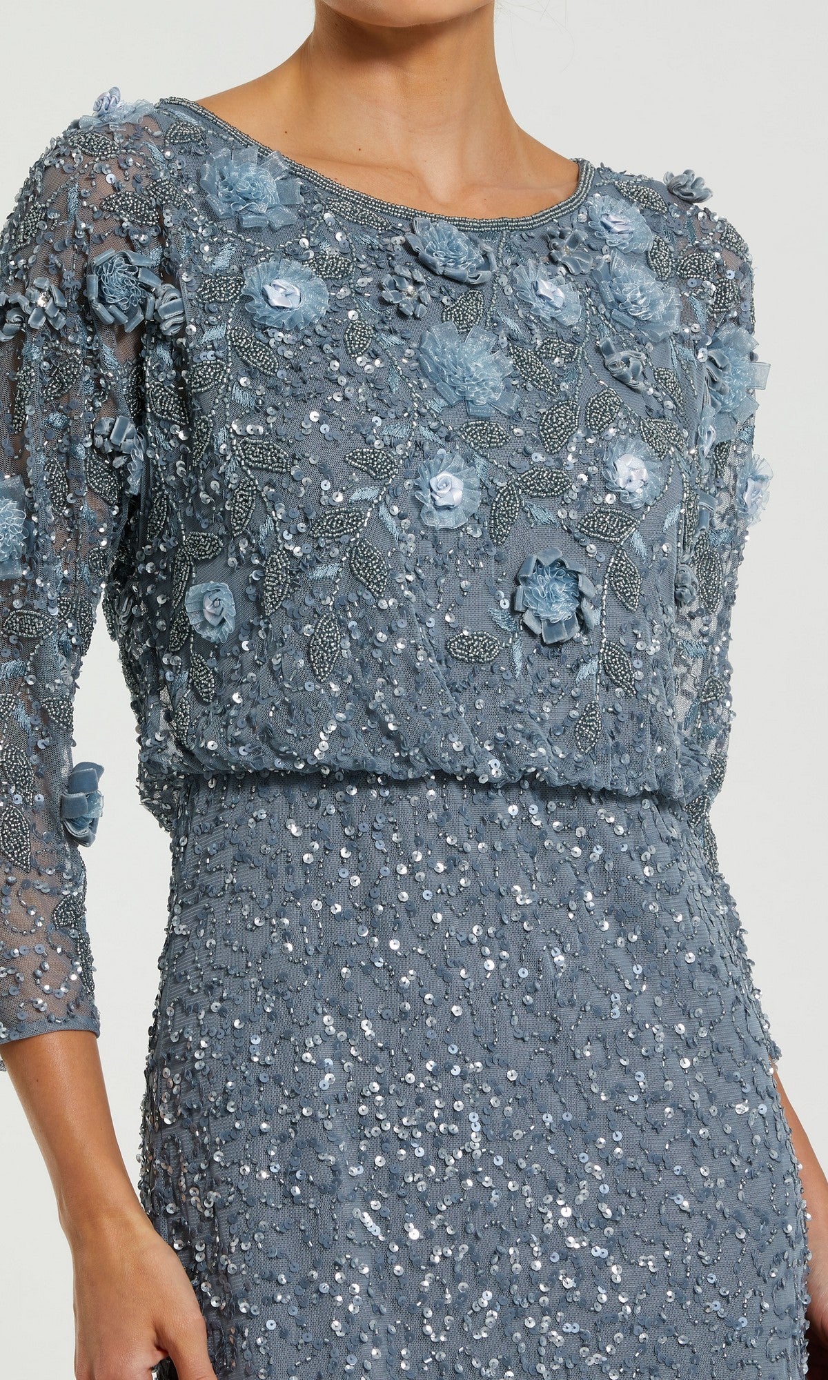 A woman wearing the Mac Duggal 9373 Tea-Length Wedding Guest Dress, featuring blue three-quarter sleeves, exquisite floral embroidery and sequin embellishments, with delicate 3D floral accents on a light background.
