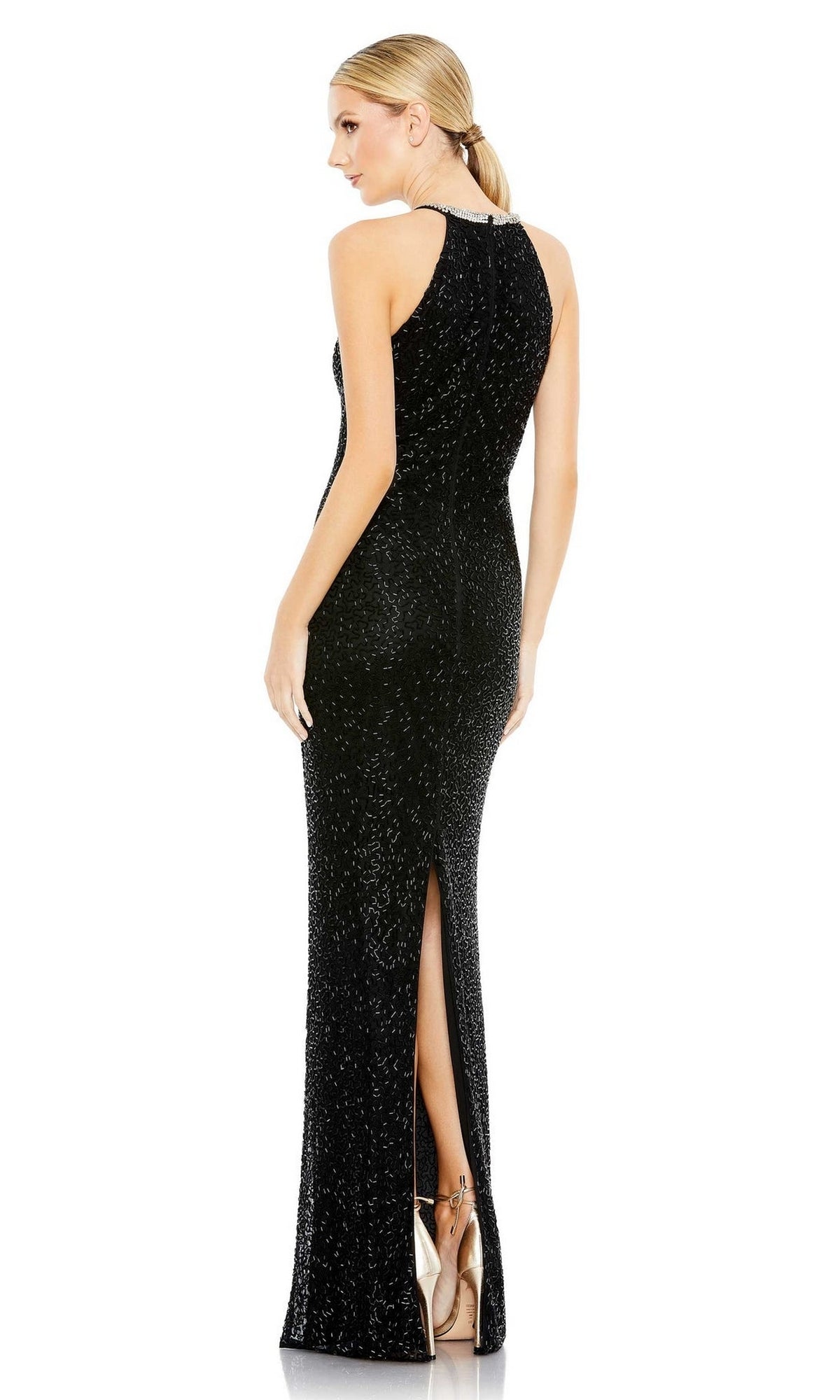 A woman stands facing away, showcasing the back of the Long Black Beaded Formal Dress: Mac Duggal 93742—a sleeveless, floor-length gown with black sequins and a back slit. Her hair is styled in a low ponytail.