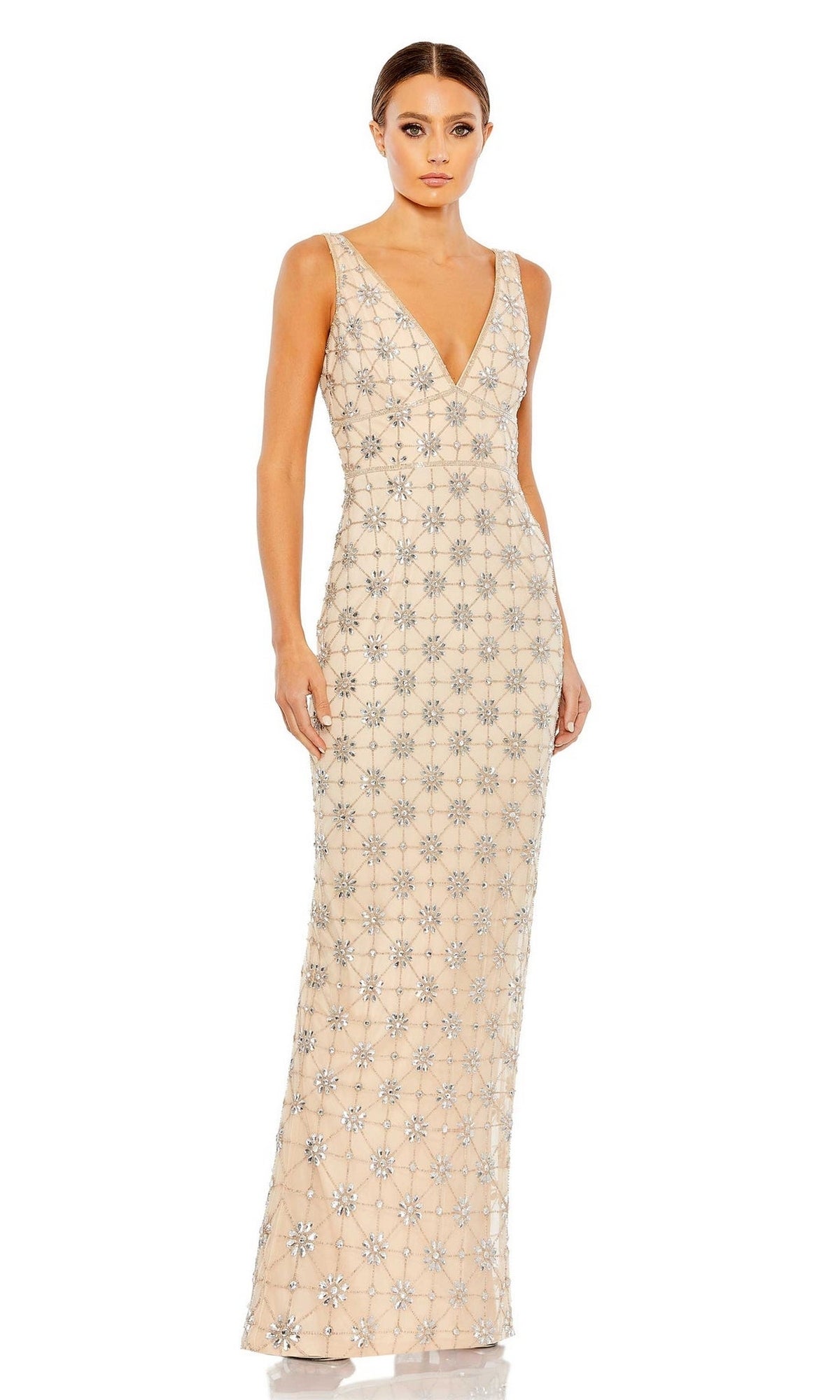 A woman stands against a white background wearing the Mac Duggal 93744 V-Neck Long Beaded Formal Dress, a sleeveless, floor-length gown adorned with silver geometric embellishments.