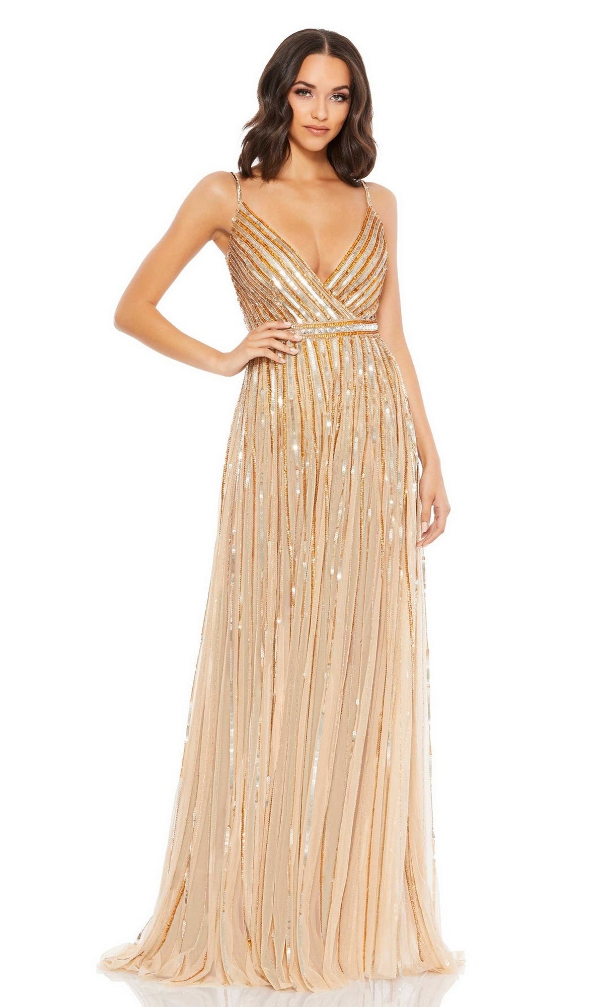 A woman stands against a white background, wearing the Long Formal Dress 93801 by Mac Duggal. This floor-length, sleeveless gown features gold embellishments, a deep V-neckline, and sparkling sequins for an elegant, glamorous look.