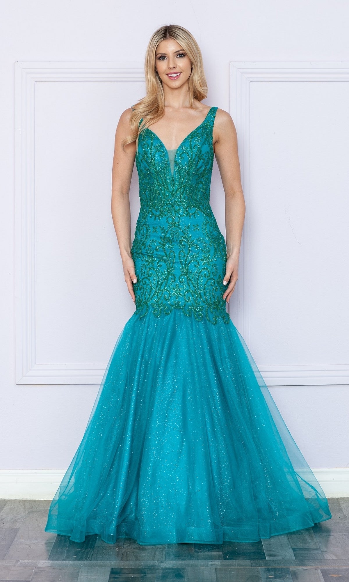 A woman poses against a light wall in the Low V-Neck Long Glitter Mermaid Prom Dress 9388 in teal, featuring sparkling details.