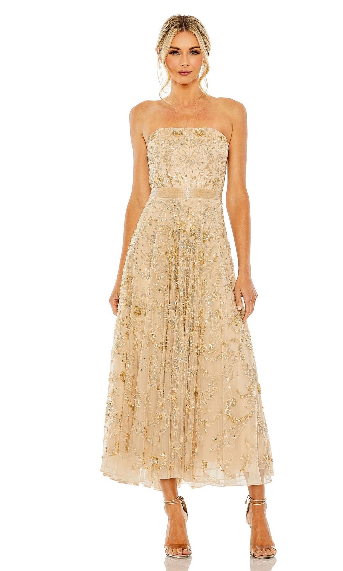 A woman stands in heels against a plain white background, wearing the Strapless Wedding Guest Dress: Mac Duggal 93898 in beige with gold floral embroidery.