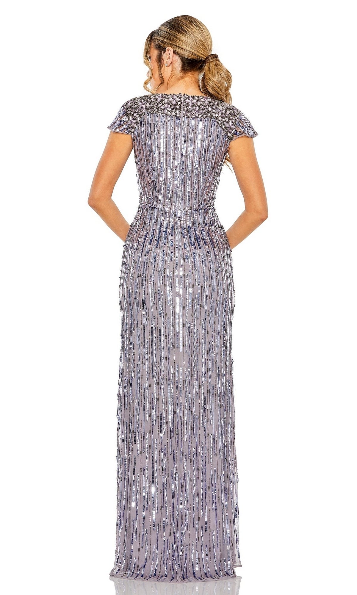 A woman with her hair in a ponytail faces away, wearing the Mac Duggal Heather Gray Sequin Formal Dress 93914—a floor-length, short-sleeve gown featuring a beaded bodice and silver vertical sequined embellishments.
