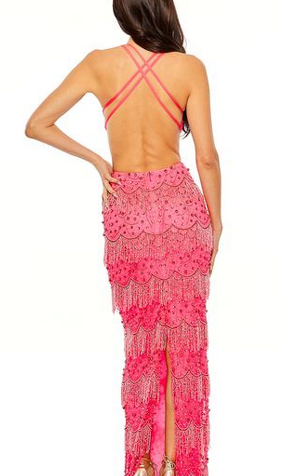 A woman stands facing away, wearing the Mac Duggal Backless Beaded Formal Dress 93956—a bright pink v-neck gown with crisscross straps, beaded fringe layers, and intricate detailing.