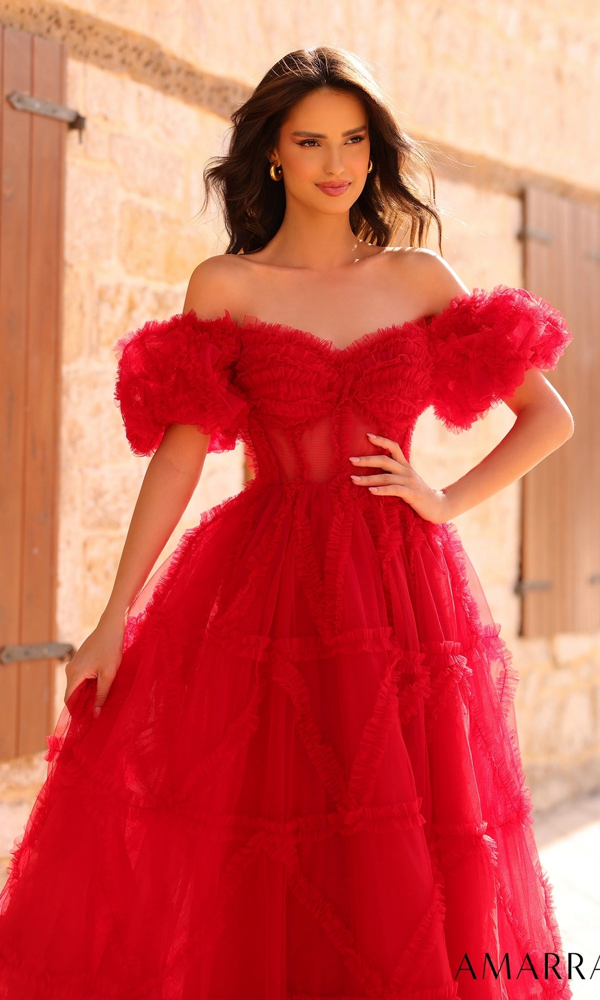 A woman stands outdoors in sunlight wearing the Amarra Puff-Sleeve Long Ruffled Prom Dress 94002. Soft waves frame her face as the light highlights the dress’s ruffled layers and elegant sheer details.