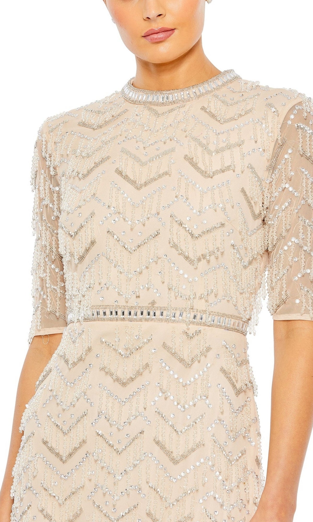 A woman wears the Mac Duggal Beaded Fringe Long Formal Dress 94071, a beige gown with sequin and bead chevron detailing, short sleeves, high neckline, and delicate beaded fringe for elegant flair.