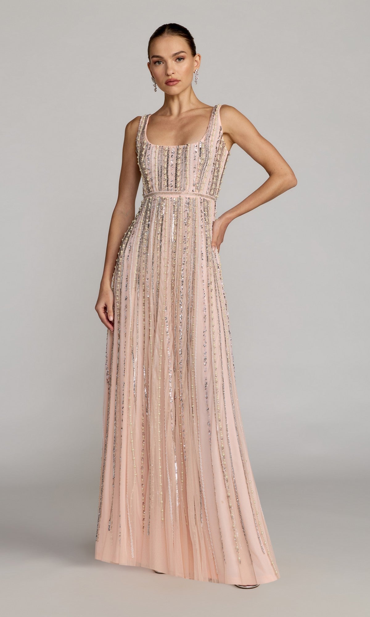 Woman wearing the Mac Duggal 94080 Long Beaded Blue Formal Dress, a sleeveless, floor-length gown with vertical silver sequin embellishments, stands against a plain gray background.