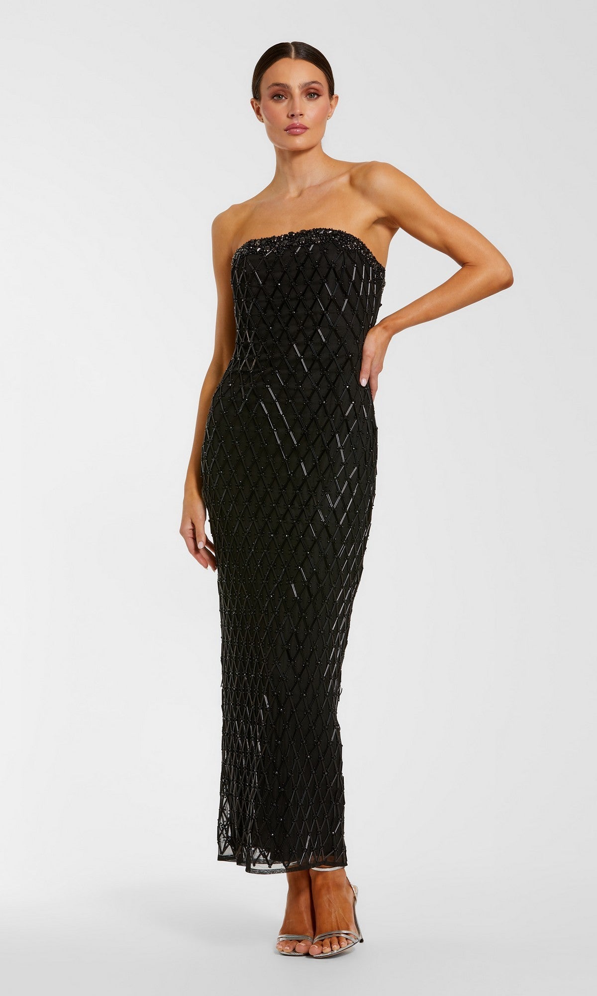 A woman poses against a plain light background in the Mac Duggal 94288 Tea-Length Party Dress in black, featuring a strapless design with a diamond-patterned overlay, paired with silver heels.