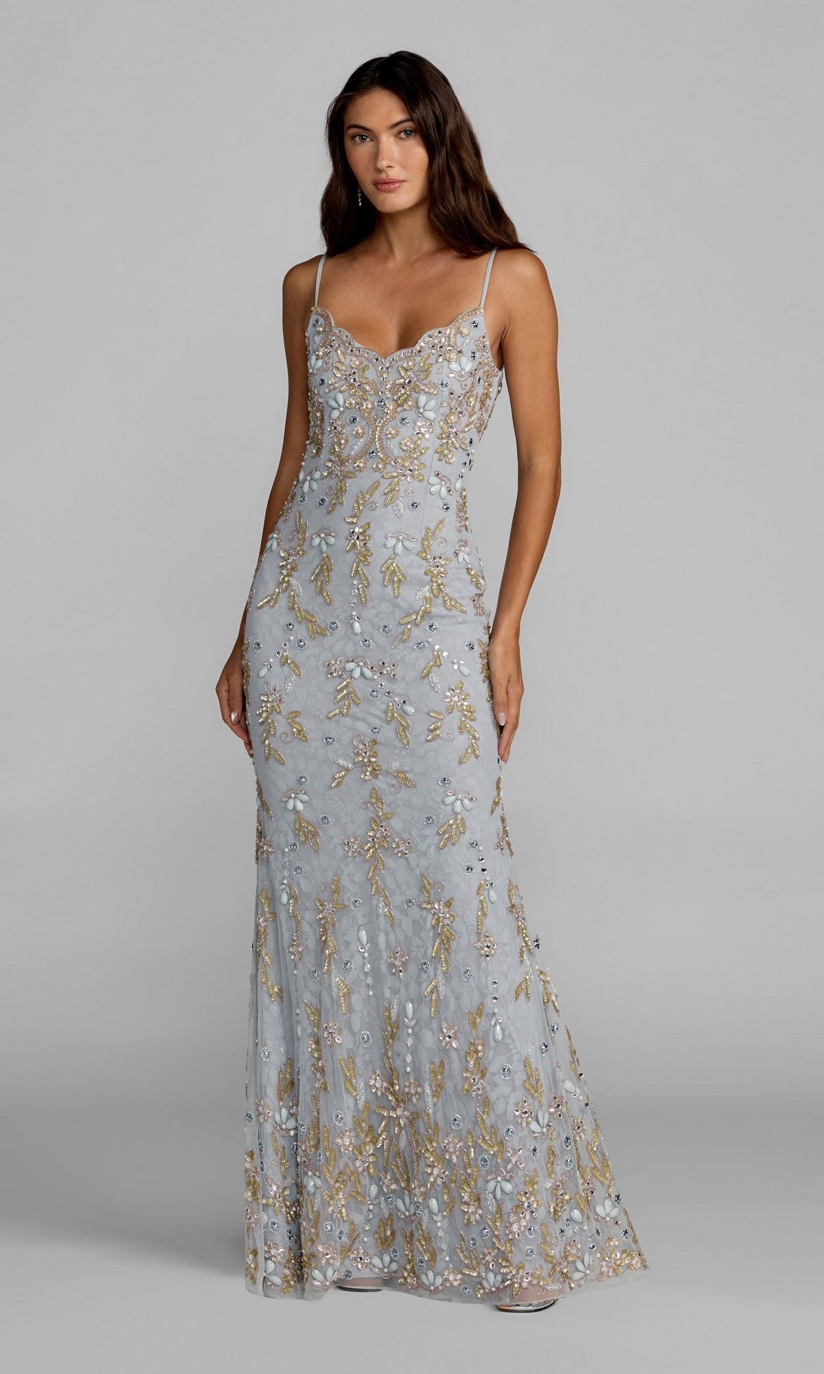 A woman wearing the Mac Duggal 94311 long formal dress in powder blue, featuring gold and silver floral embroidery, stands against a plain gray background.