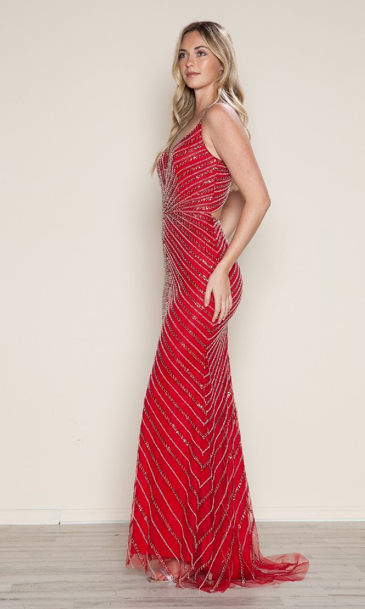 A woman in profile models the Poly USA 9530 Cut-Out Long Beaded Prom Dress— a sleeveless, floor-length red gown with diagonal silver sequin stripes, set against a plain beige background.