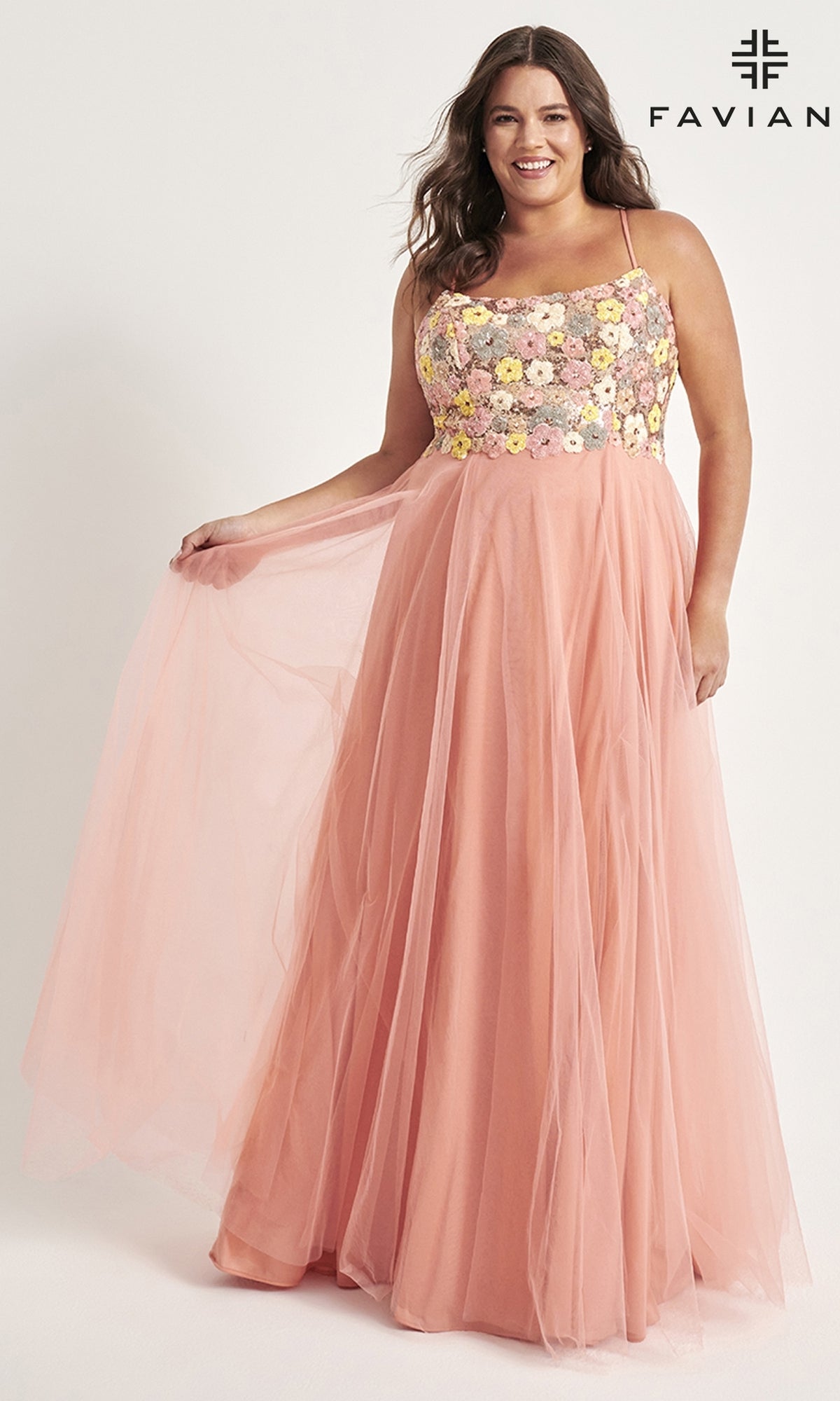 A woman poses against a plain background in the Faviana Floral Plus-Size Long Prom Dress 9557—a sleeveless, floor-length pink gown featuring a beautifully embroidered floral bodice.