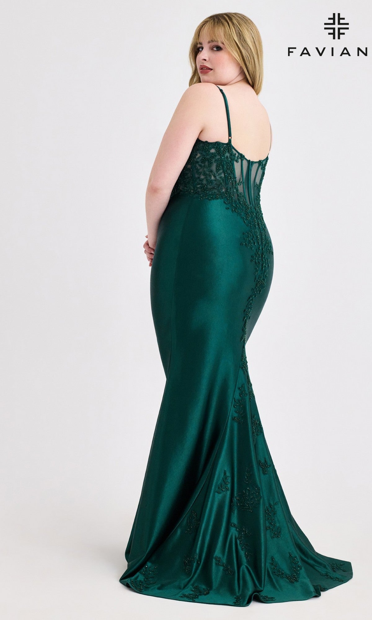 A woman in a green, floor-length, sleeveless plus-size Beaded-Corset Prom Gown (Faviana 9600) stands facing away from the camera. The Faviana logo is in the top right corner.