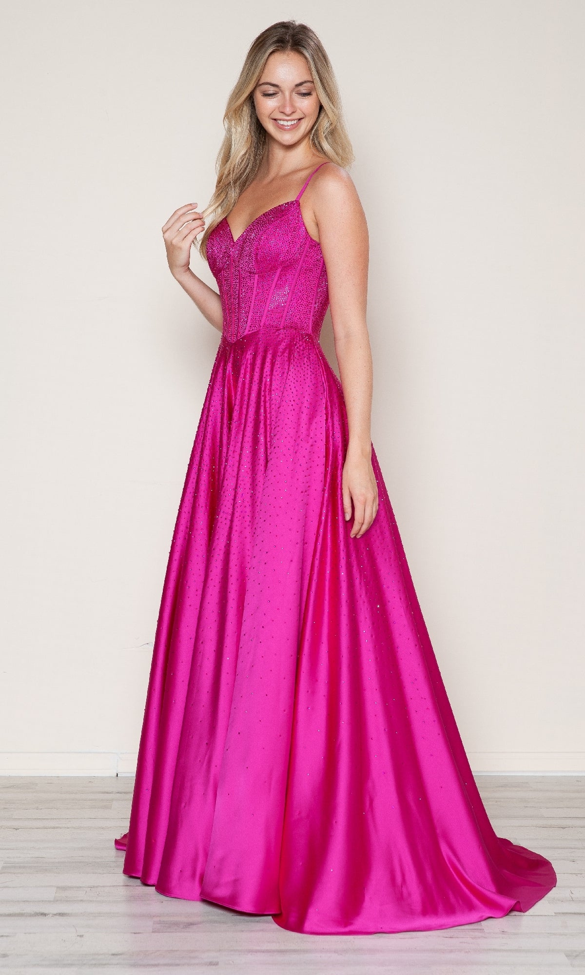 A woman wears the Poly USA 9610 long prom dress in bright pink, featuring a floor-length A-line silhouette, fitted bodice, and thin straps, standing on a light-colored floor against a plain background.