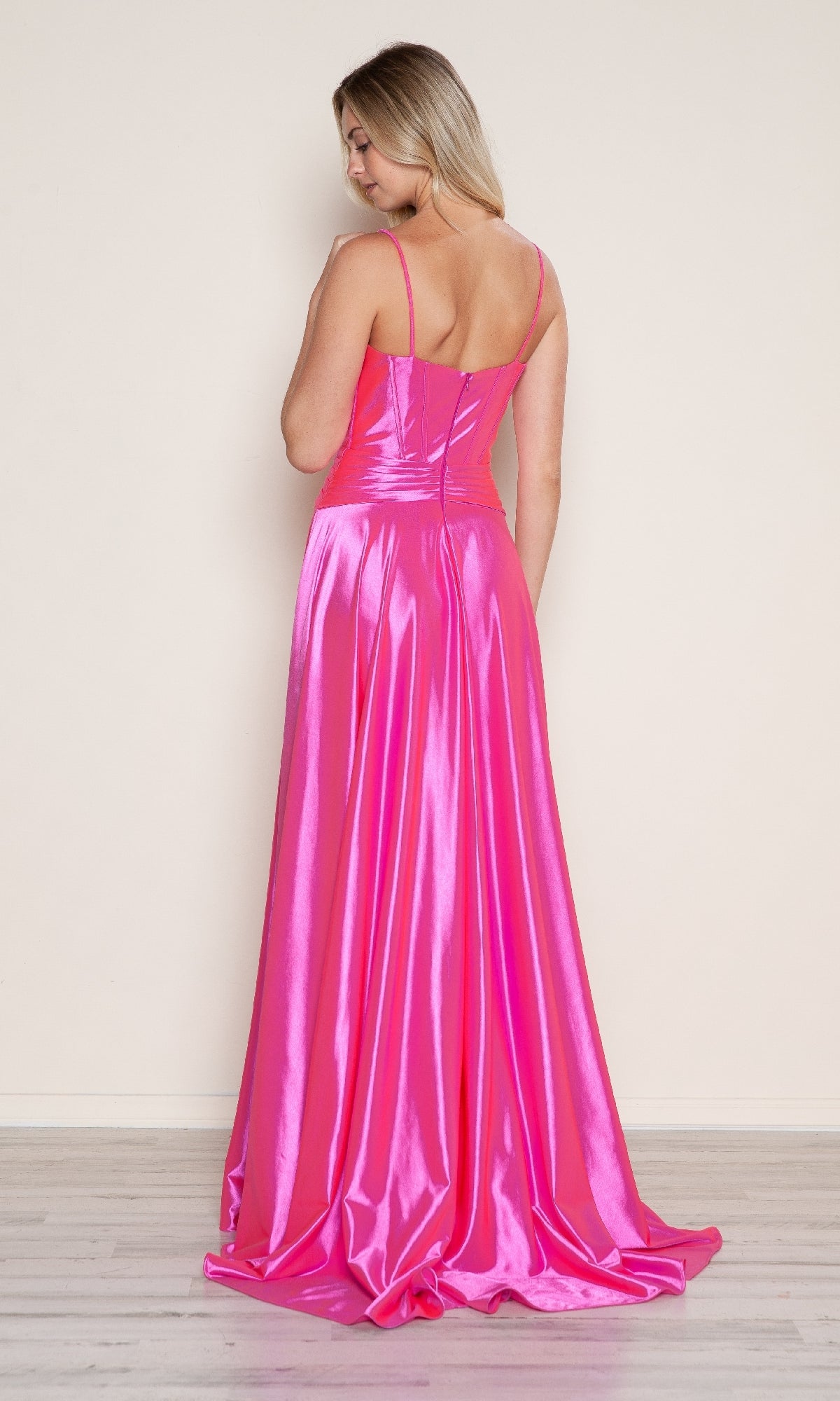A woman models the Bow-Front Long Corset Prom Dress (Poly USA 9702), a shiny hot pink satin evening gown with thin straps and an open back corset detail, standing against a plain light background.