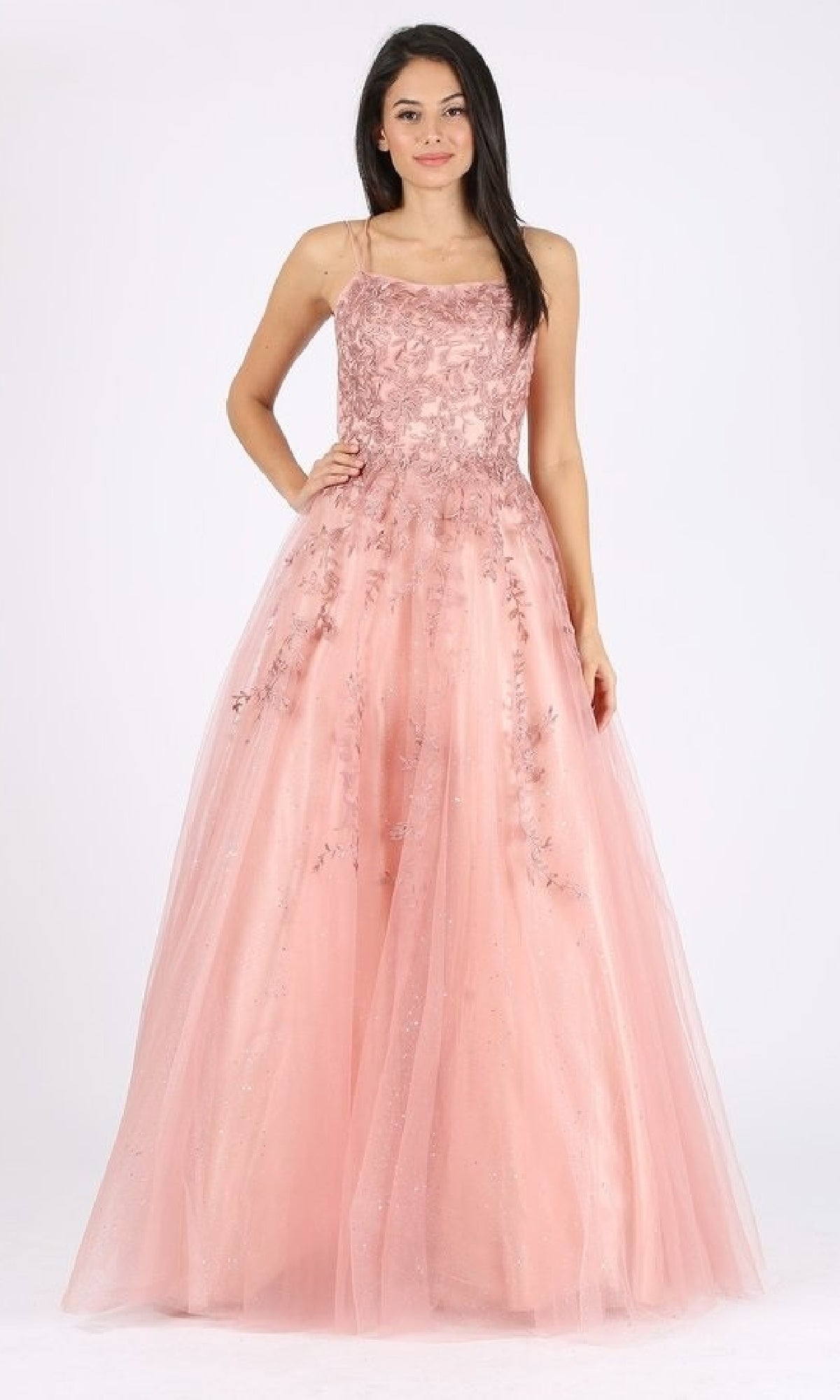 A woman poses in the Lace-Up Long Lace Prom Ball Gown: Eureka CC0240, featuring a fitted bodice, lace-up back, and full tulle skirt. The embellished pink gown looks elegant against a plain white background.