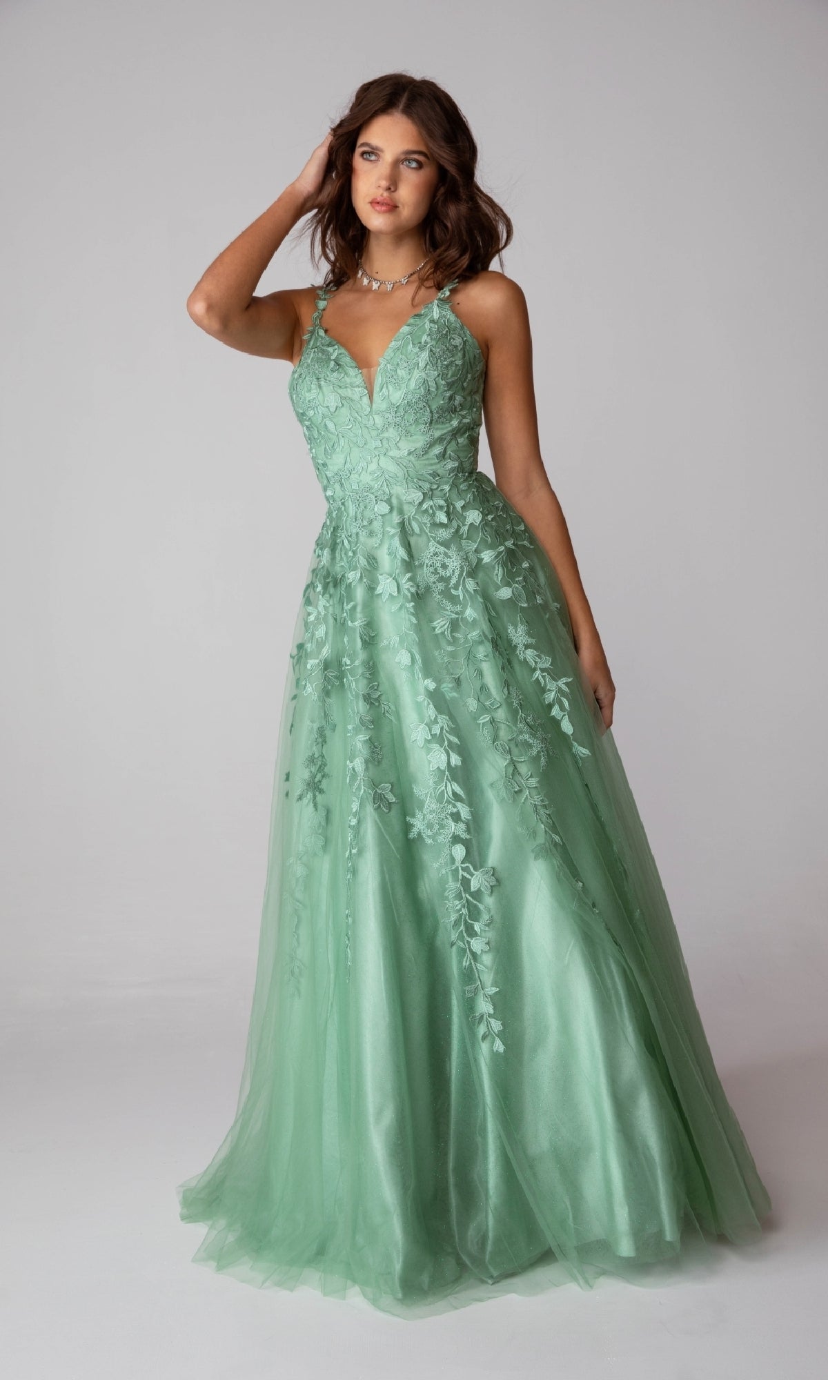 A woman models the Eureka 9858 Embroidered-Lace Long Prom Dress, a sleeveless light green gown with floral embroidery, standing against a plain background.