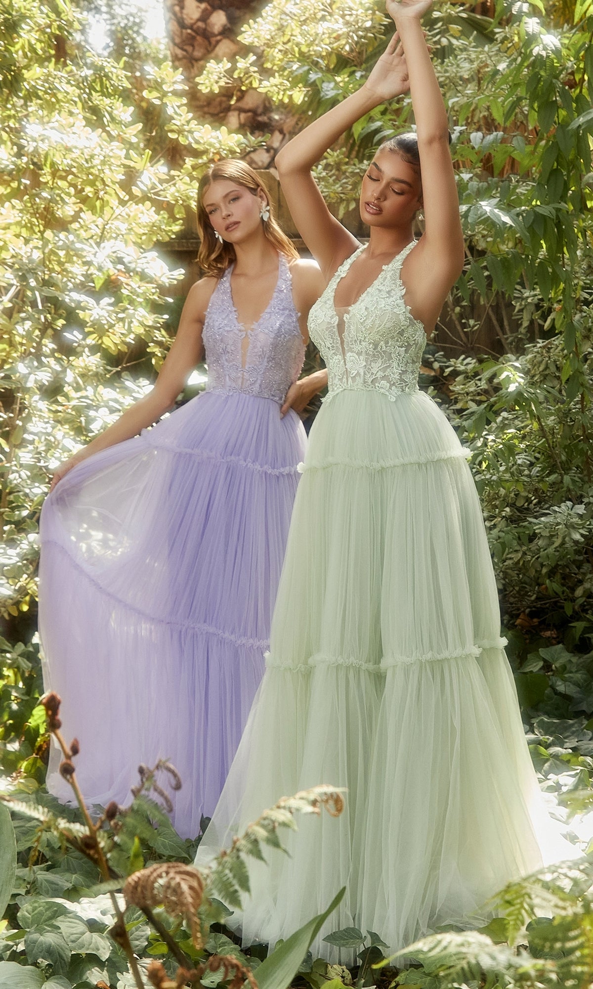 Two women in a garden wear the Lace-Halter Long A-Line Prom Dress A1206—one in lavender, one in pale green—each featuring a floral-lace bodice and layered tulle skirt for a dreamy, graceful look.