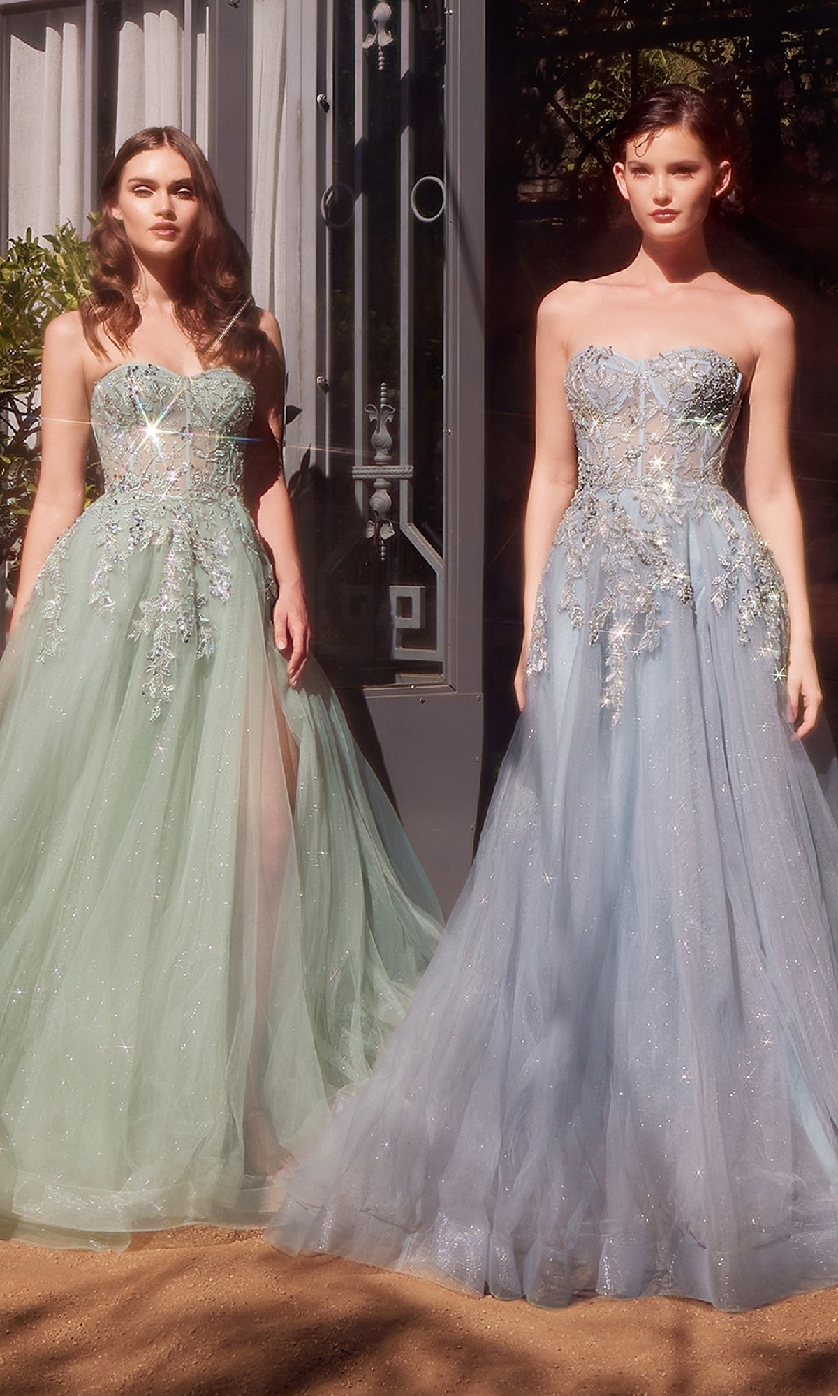 Two women stand outdoors in Andrea & Leo A1415 Strapless Prom Ball Gowns—one green with floral embellishments, the other a light blue sweetheart style—both featuring beaded, sheer bodices.