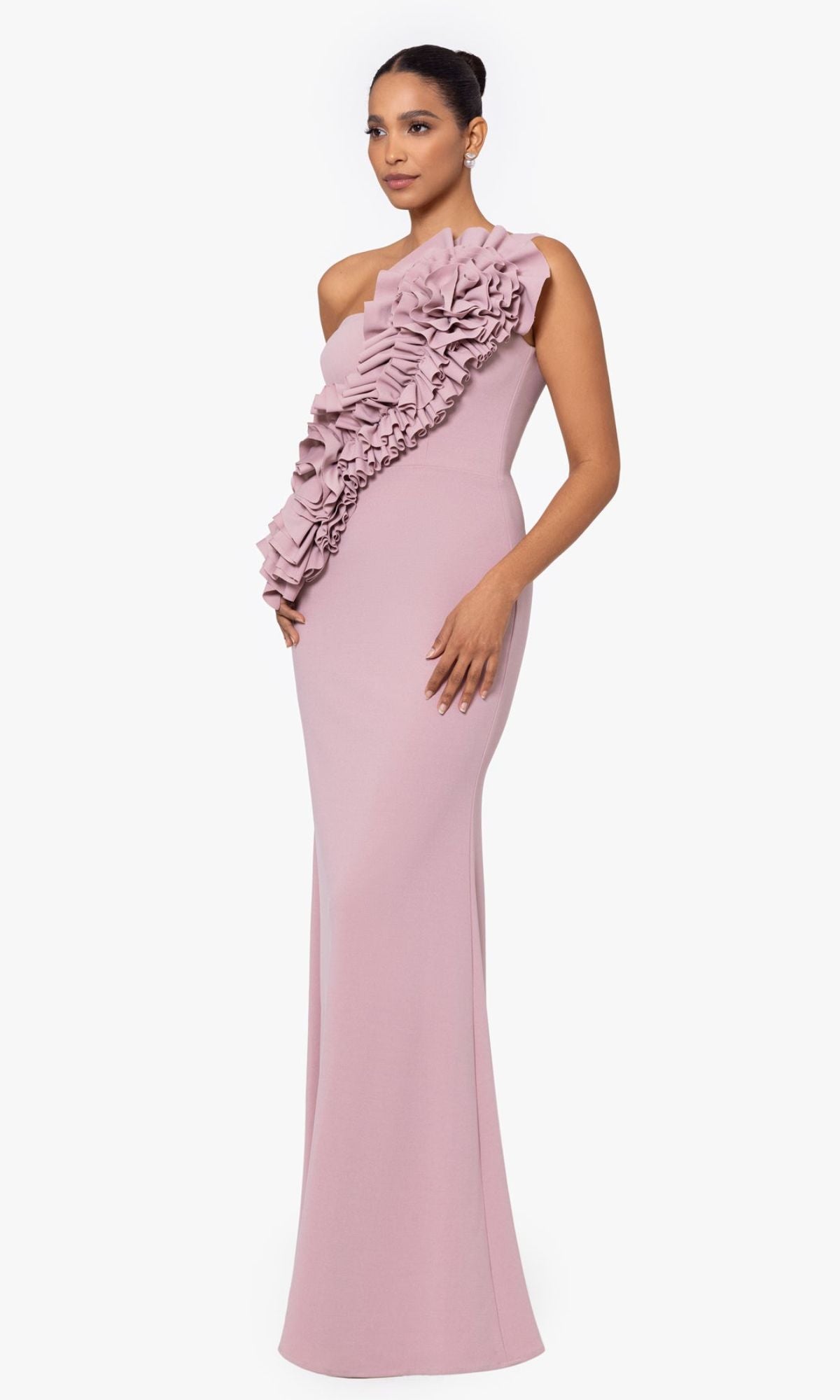 Woman wearing the Betsy and Adam One-Shoulder Long Prom Dress A26071, a fitted mauve gown featuring an asymmetrical neckline and a large ruffle detail across the front.