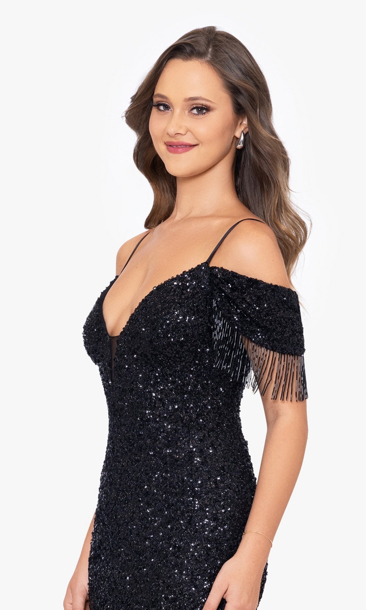Woman in the Fringed Long Black Beaded Prom Dress A26115, a formal off-shoulder gown with sequin and fringe details, standing and smiling against a white background.