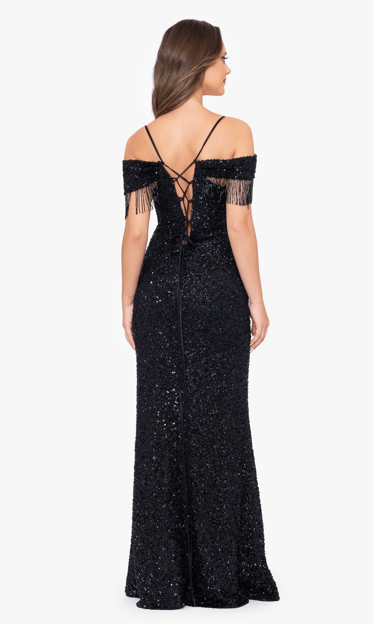 A woman is seen from behind wearing the Fringed Long Black Beaded Prom Dress A26115, featuring an off-the-shoulder neckline, lace-up back, floor-length silhouette, and fringe details against a plain background.