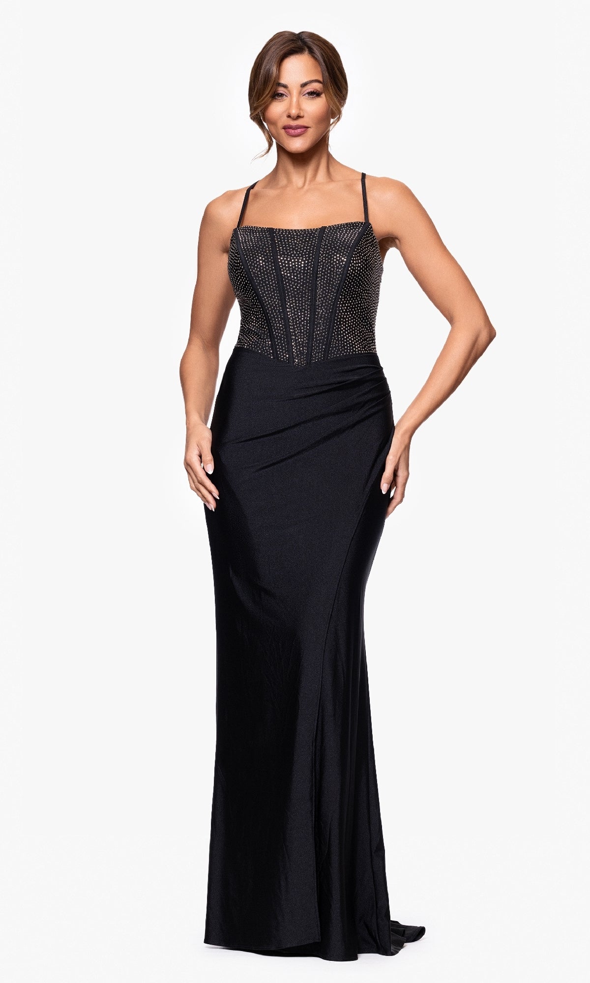 A woman models the Betsy and Adam A27256 long formal dress with a black embellished corset bodice and floor-length skirt, standing against a plain white background.