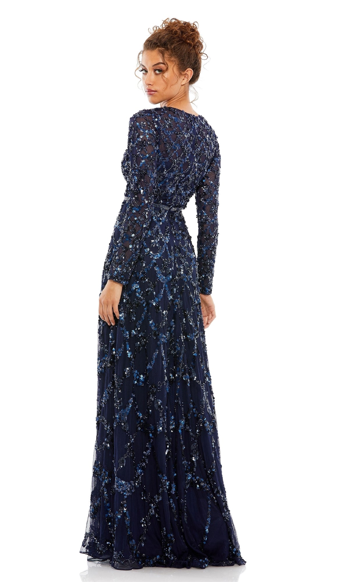 A woman faces away wearing the Mac Duggal 5496 Long Sleeve Sequin Formal Gown, a navy blue evening dress with intricate beaded details—an ideal choice for a mother of the bride.