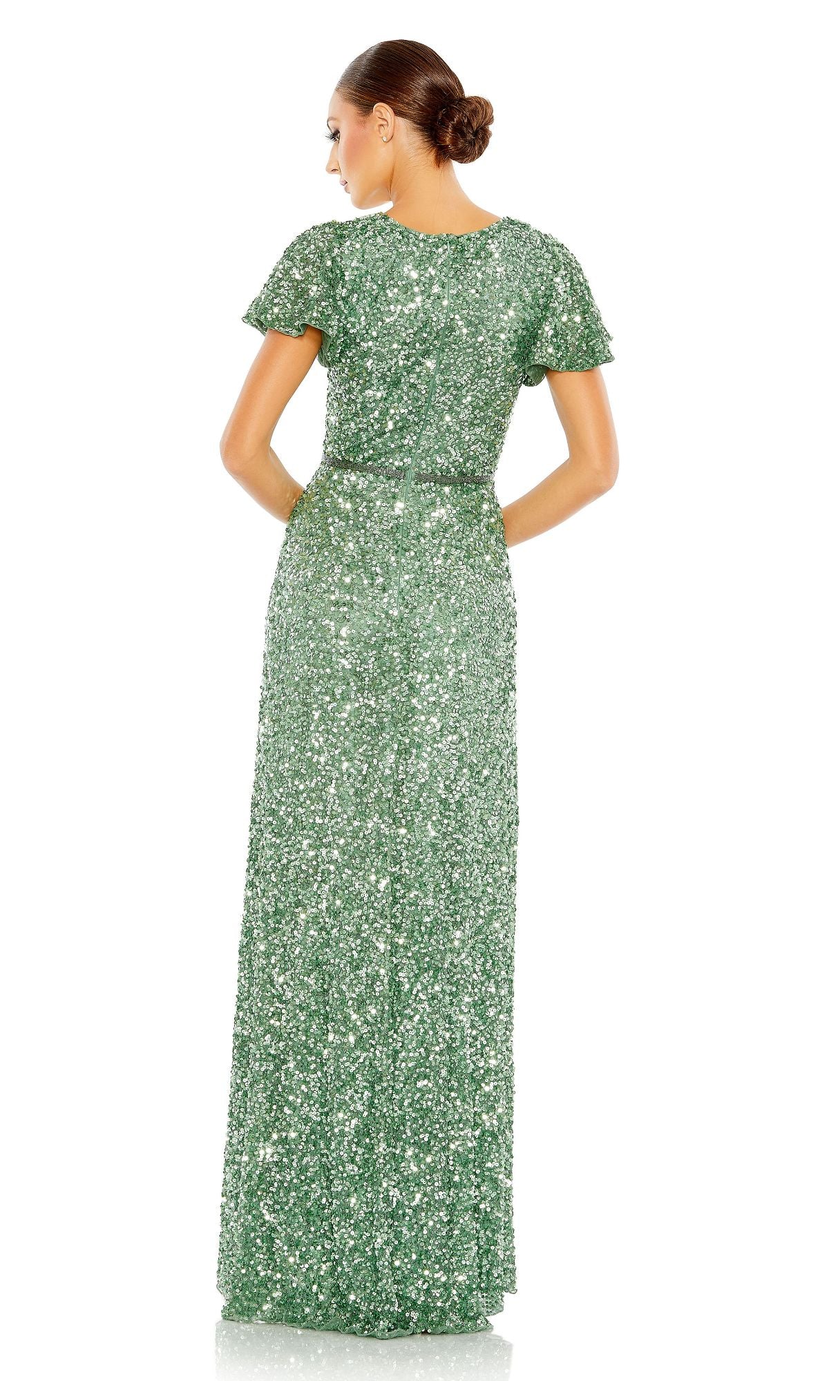 A woman with her hair in a neat bun faces away, wearing the floor-length green Mac Duggal 5540 Short-Sleeve Sequin Formal Dress.