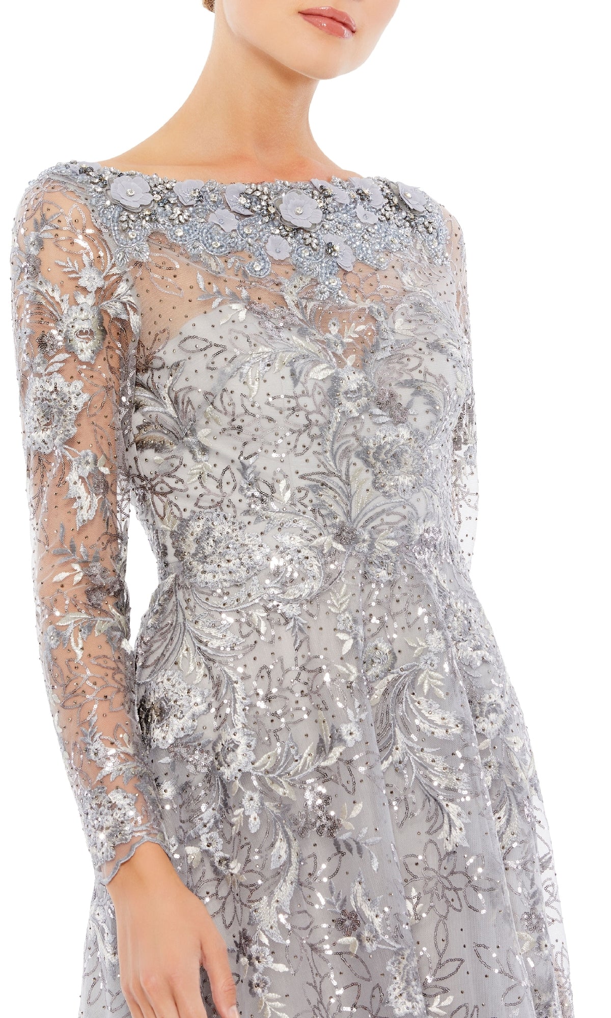A woman models the Mac Duggal 67498, a long sleeve formal dress with sheer fabric, silver embroidery, floral accents, and sequins, photographed from shoulders to knees against a white background.