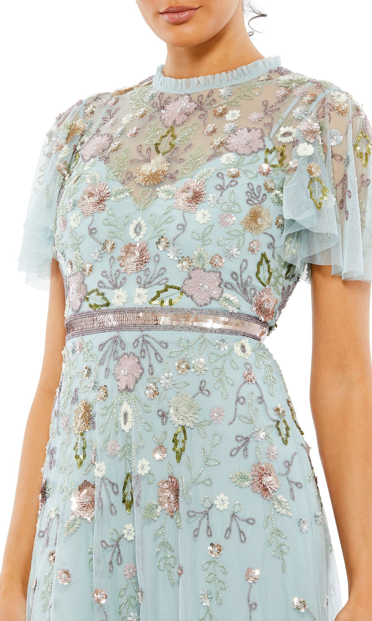 A woman wears the Mac Duggal Long Formal Dress 9136, featuring a light blue beaded A-line silhouette, multicolored floral embroidery, short sheer sleeves, and a high neckline.