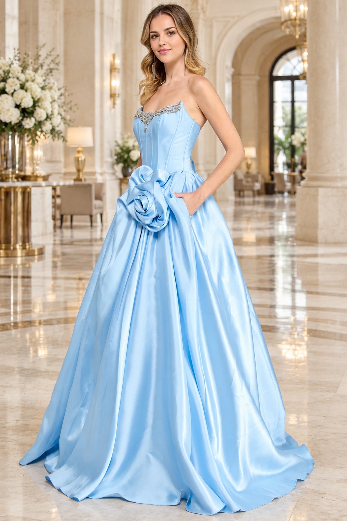 A light blue Corset Prom Ball Gown: Amelia Couture AL1401 strapless gown with a rhinestone-embellished neckline and a large fabric flower accent at the waist.