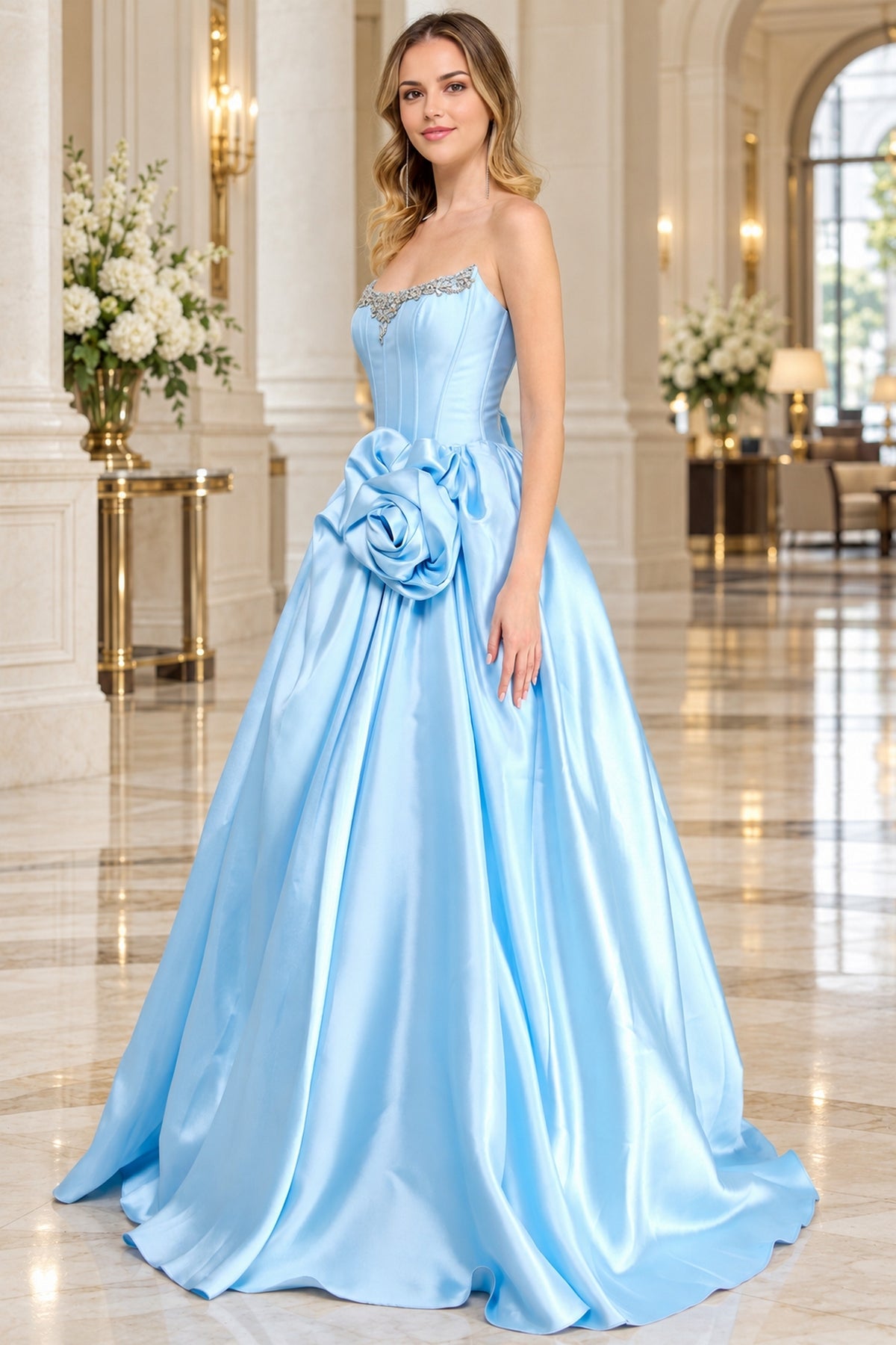 A strapless light blue Corset Prom Ball Gown: Amelia Couture AL1401 featuring a corset-style bodice with beaded trim and a large floral accent at the waist.