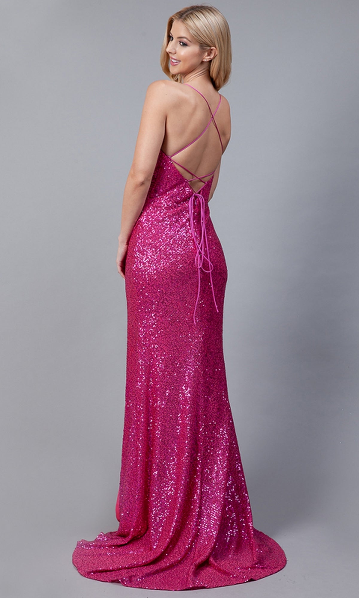 A woman faces away, wearing the Faux-Wrap Long Sequin Prom Dress BZ011—magenta, floor-length, backless, with thin crisscross straps—set against a plain gray background.