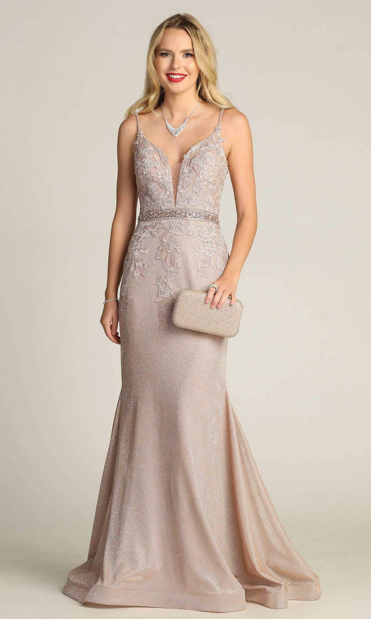A woman wears the Chicas C243 Low-Back Long Mermaid Prom Dress—blush, shimmery, sleeveless with lace details—styled with a matching clutch and necklace, standing against a plain background.