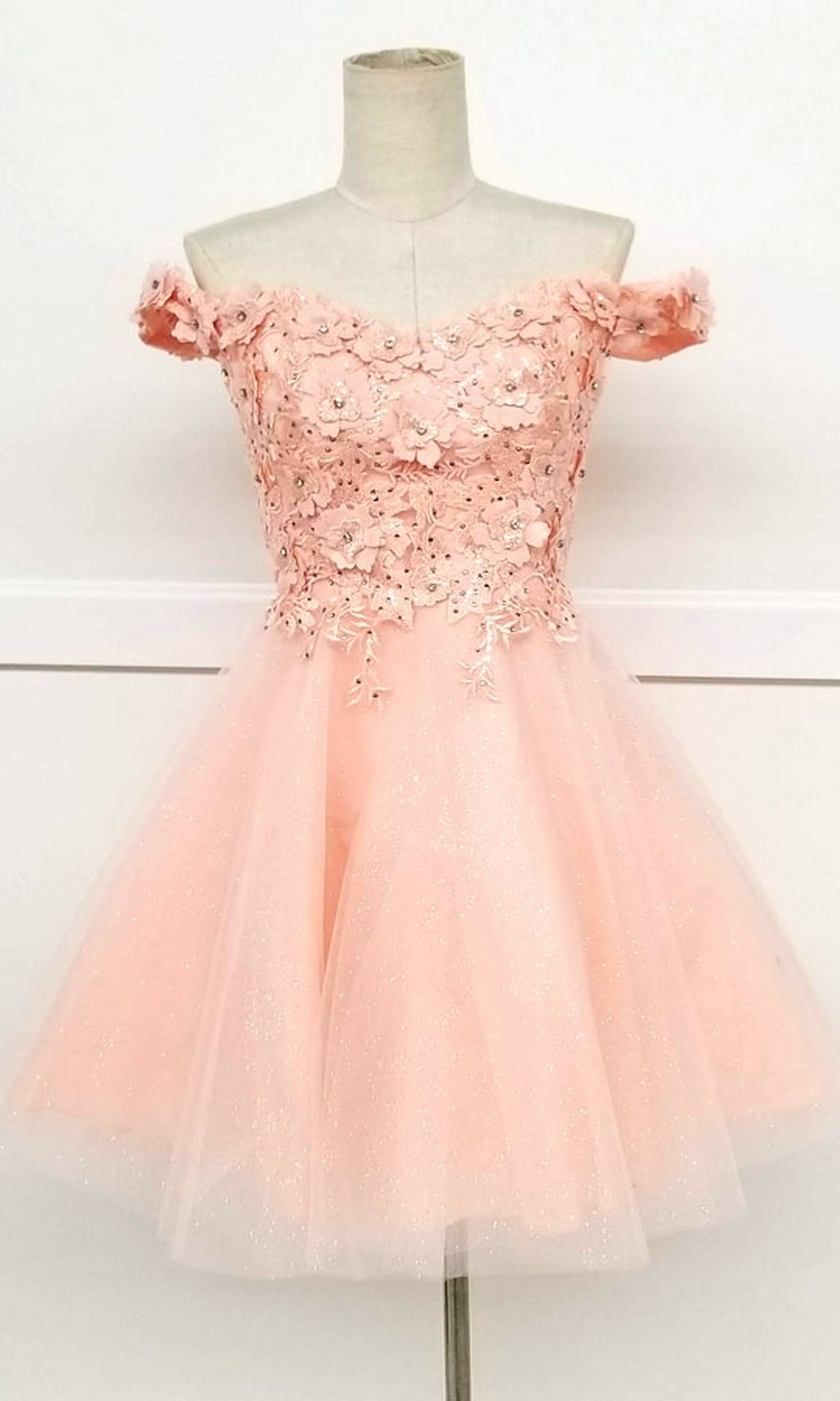 A mannequin showcases the Beaded-Bodice Short A-Line Homecoming Dress C315—a pink, off-the-shoulder party dress with a floral appliqué bodice and tulle skirt, perfect as a babydoll semi-formal dress for your next event.