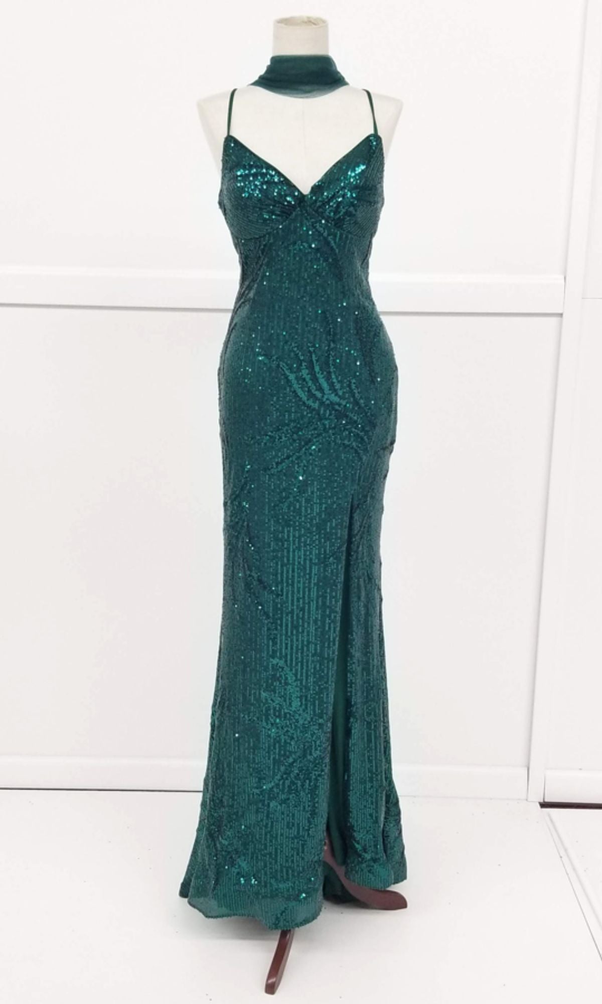 The Lace-Up Long Sequin Prom Dress: Chicas C316 is an emerald green evening gown with thin straps, fitted bodice, flared hem, and matching choker collar, shown on a dress form.