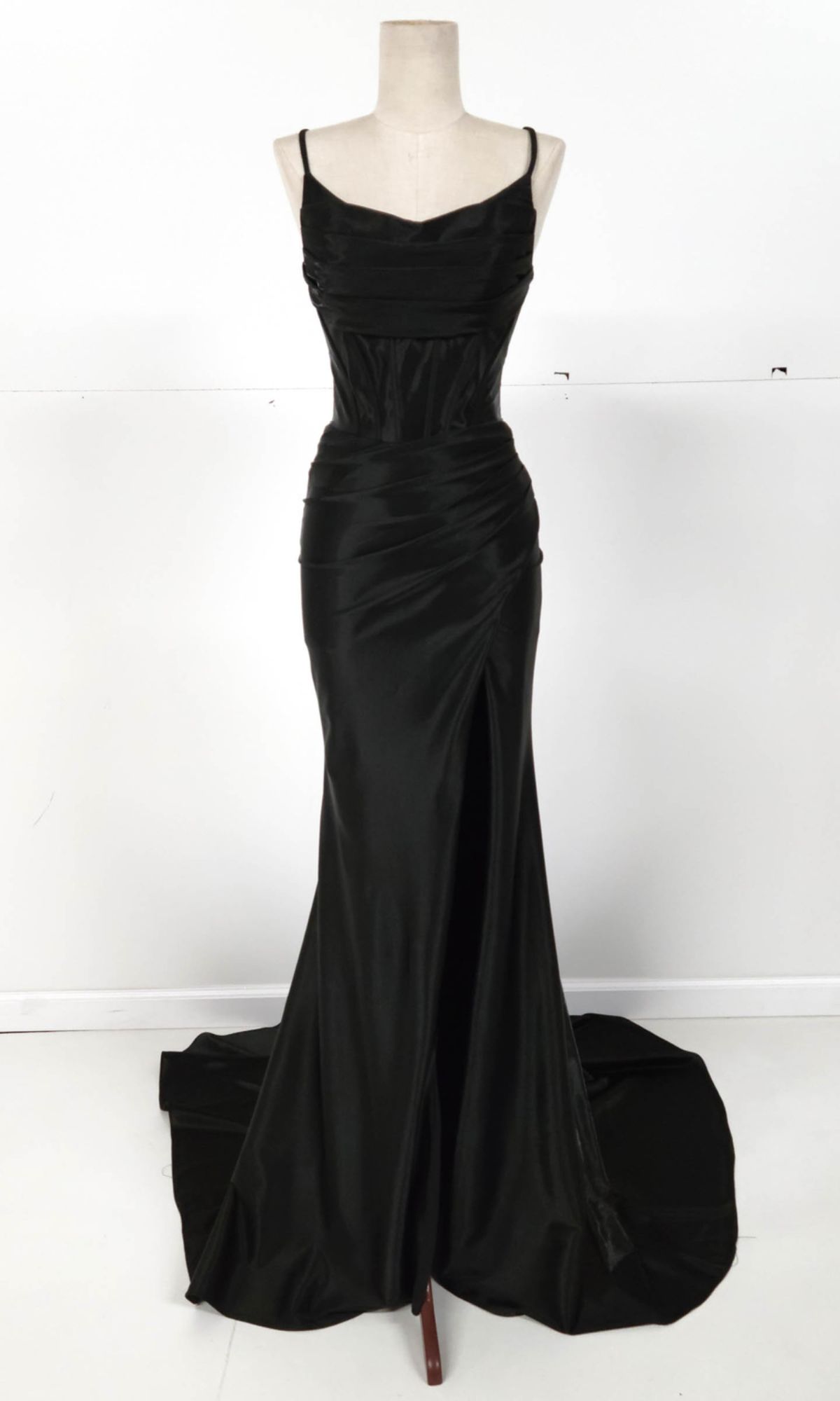 The Chicas C326 Cowl-Neck Long Prom Dress features black satin fabric, thin straps, a fitted bodice with ruched detailing, high slit, and slight train, shown on a dress form against a plain background.