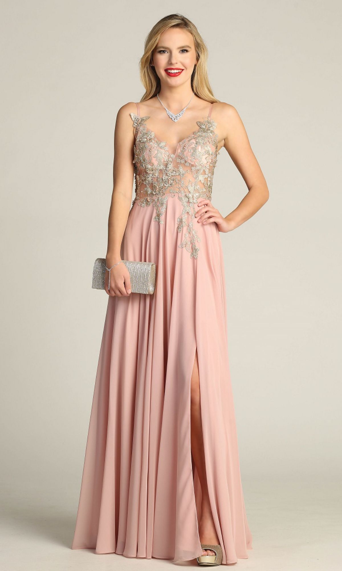 Woman wearing the Lace-Up Open-Back Long Prom Dress: Chicas C5124, a sleeveless blush pink A-line gown with floral embroidery, holding a silver clutch and wearing a necklace, stands against a plain background.