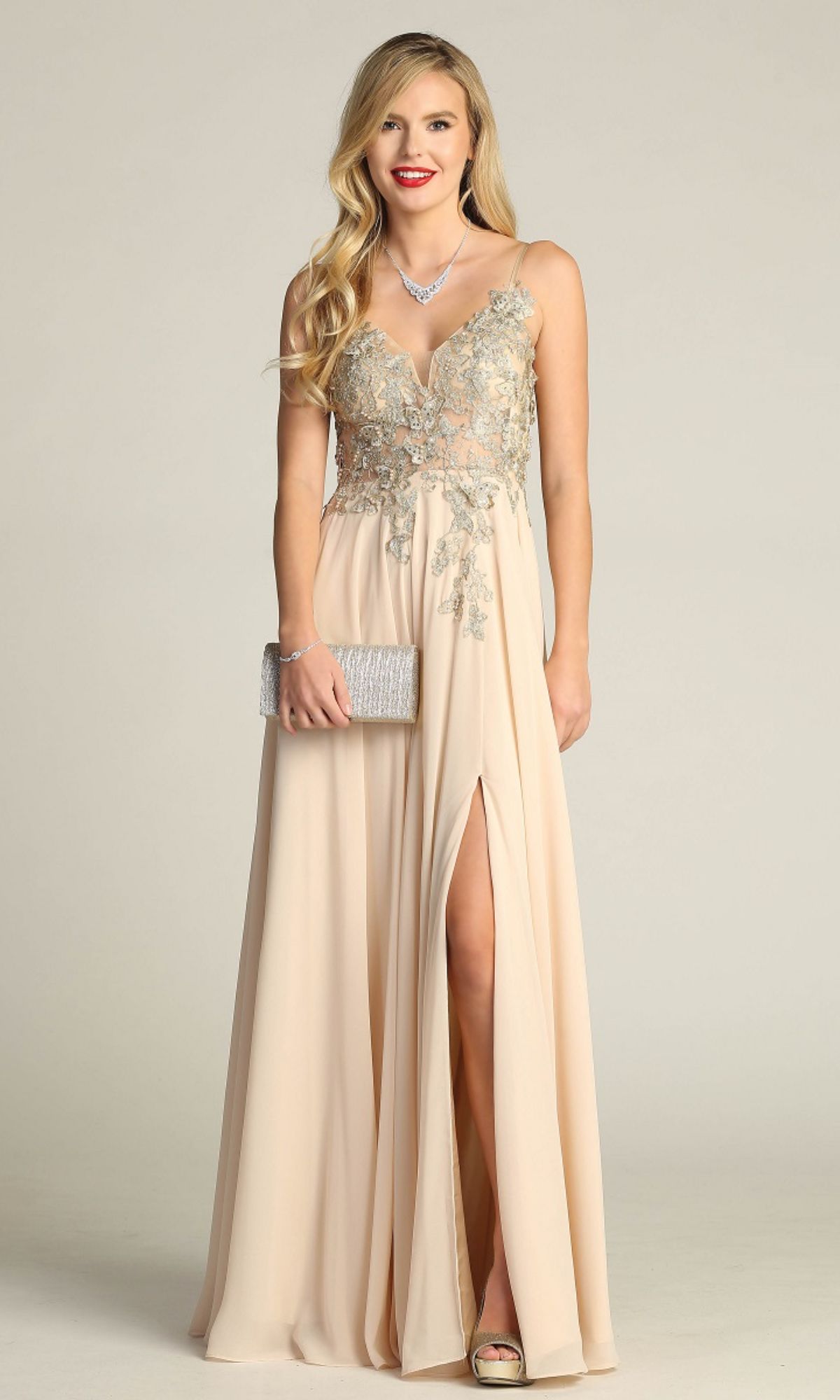 A woman in the Lace-Up Open-Back Long Prom Dress: Chicas C5124 with silver embroidery, holding a silver clutch and wearing a necklace, stands against a plain background.
