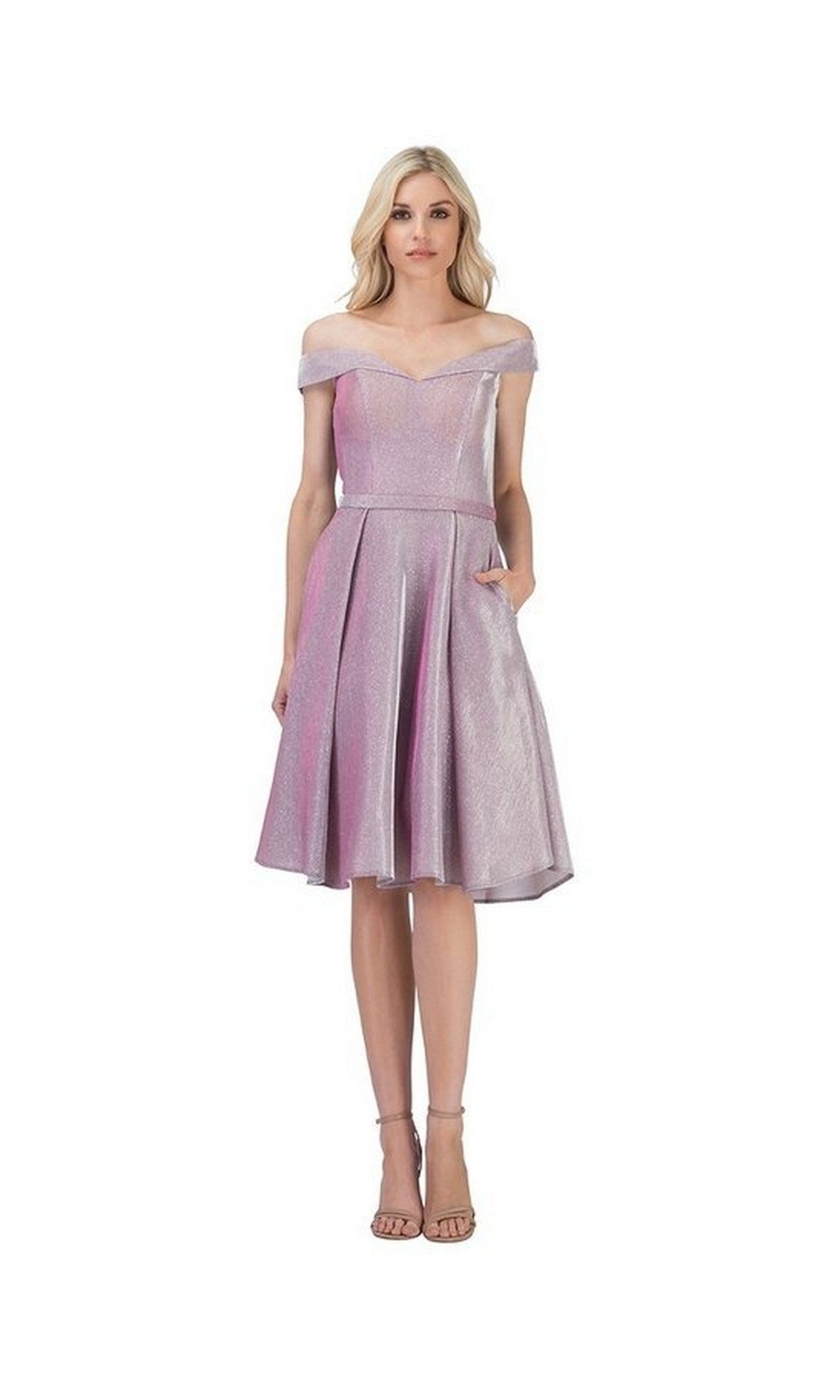 A woman stands against a plain white background wearing the Chicas C7518 short homecoming dress in lilac, featuring an off-the-shoulder neckline, a knee-length sparkly A-line skirt, and nude heels.