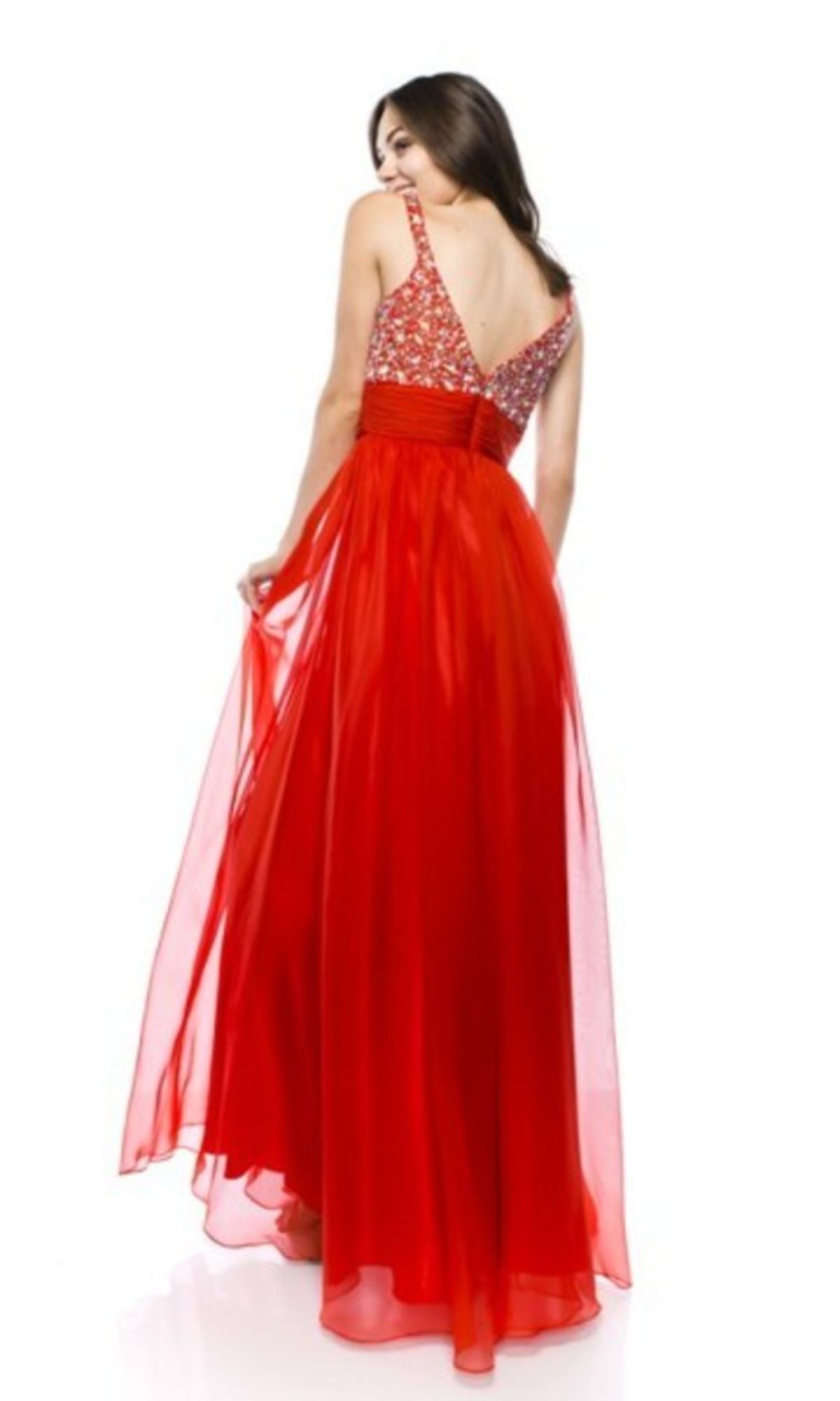 Model wearing the affordable Chicas C7816 empire-waist long prom dress with a beaded bodice, holding the gown and looking over her shoulder against a white background.