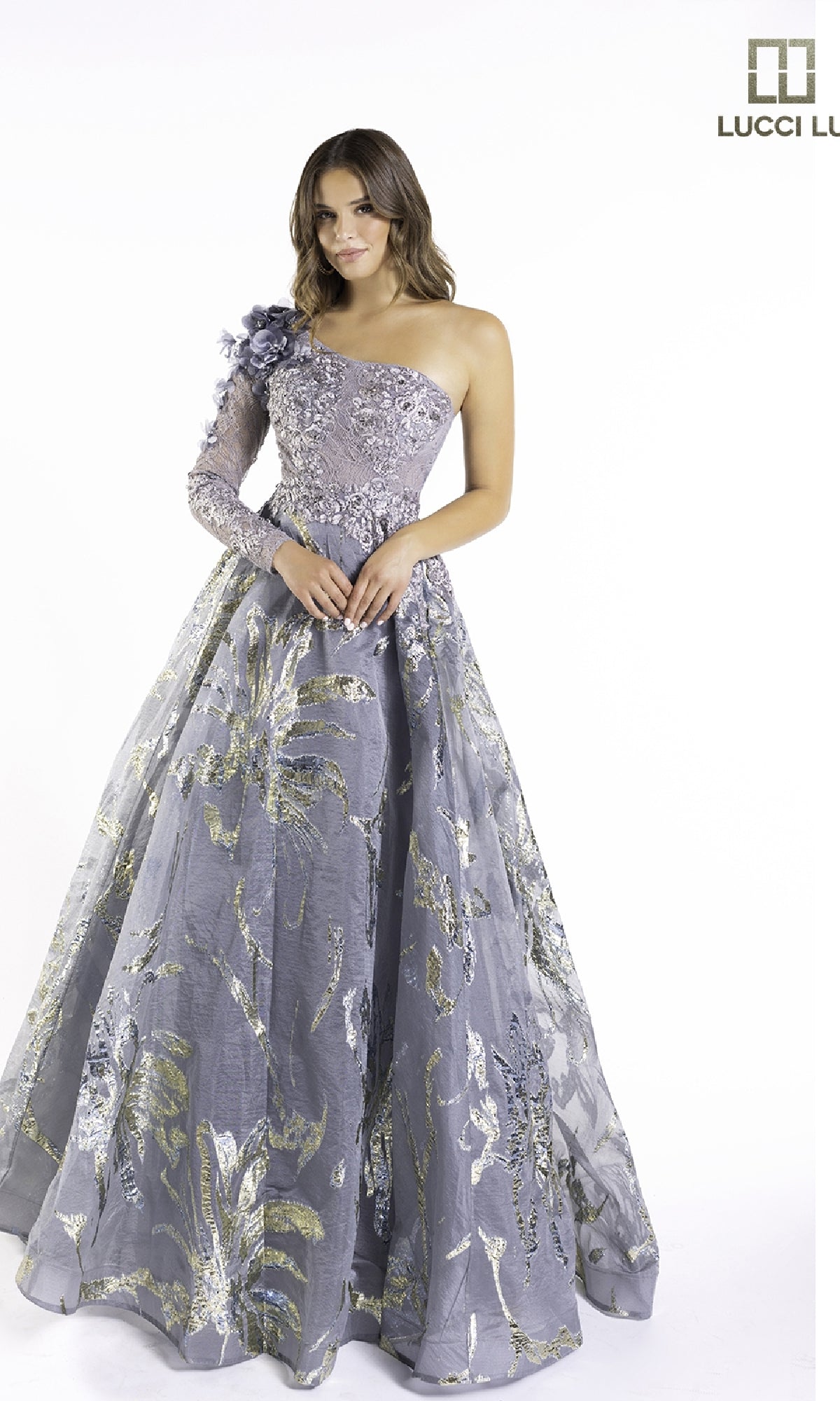 A woman models the Lucci Lu C8054 long prom dress—a lavender lace one-shoulder gown with floral embroidery and metallic accents—against a white background.
