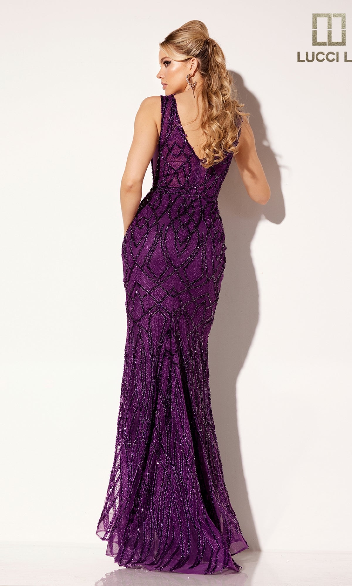 A woman with long, curled blonde hair poses with her back to the camera in the Lucci Lu C8109 sleeveless, floor-length sequined lace formal dress against a white background.