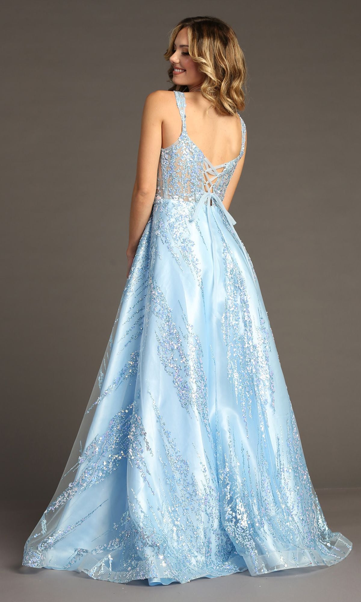 A woman in the Light Blue Long Glitter Prom Dress: Chicas C821 with a corset bodice and sparkling details stands facing away, glancing over her shoulder.