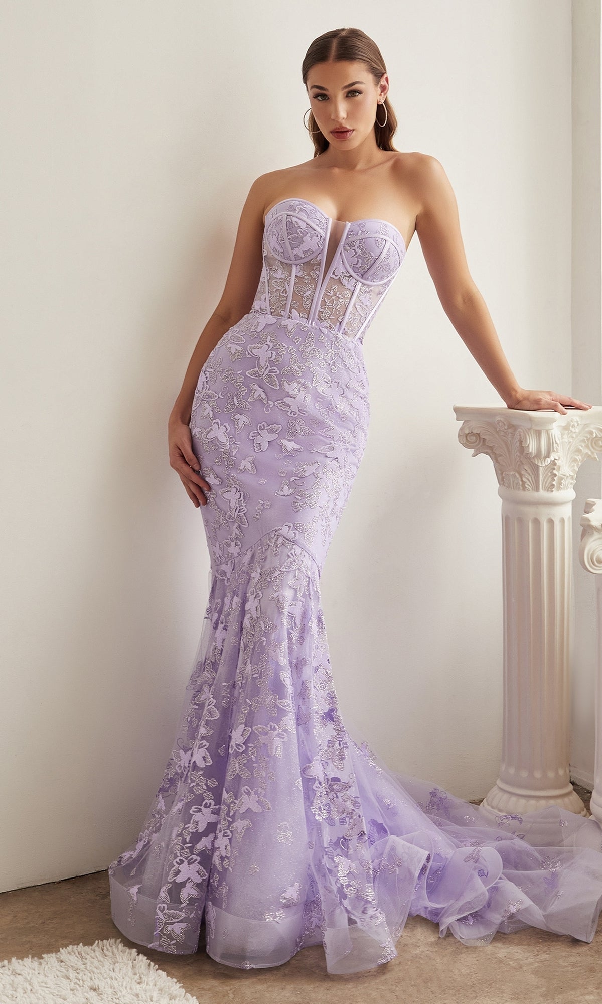 A woman wears the Butterfly-Print Strapless Mermaid Prom Dress CB099, featuring a strapless design and elegant butterfly print, as she stands beside a white decorative column.