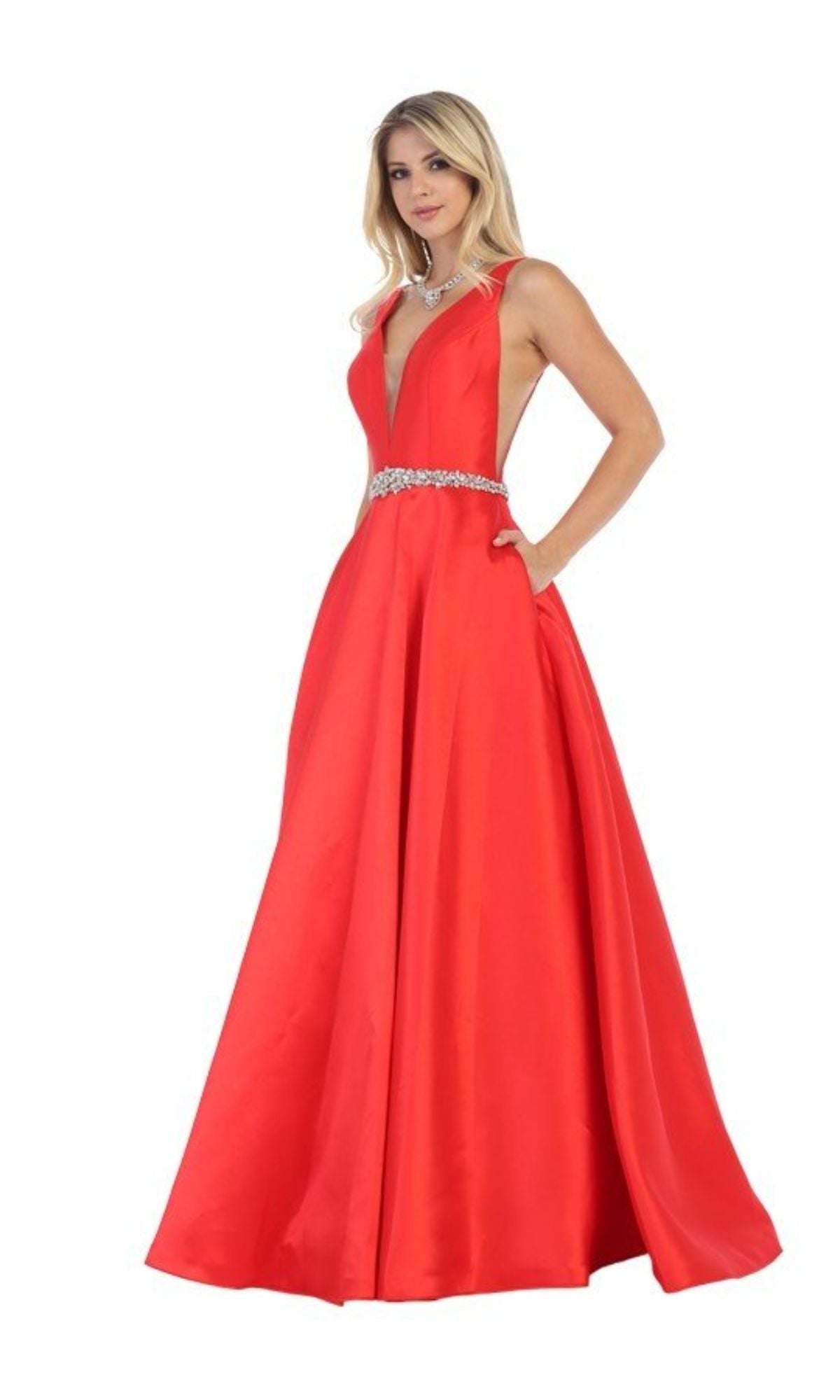 A woman poses elegantly in the Jeweled-Waist Long Prom Ball Gown: Chicas CC3021, a red A-line dress with a deep V-neckline, sparkling waist detail, and pockets, against a white background.