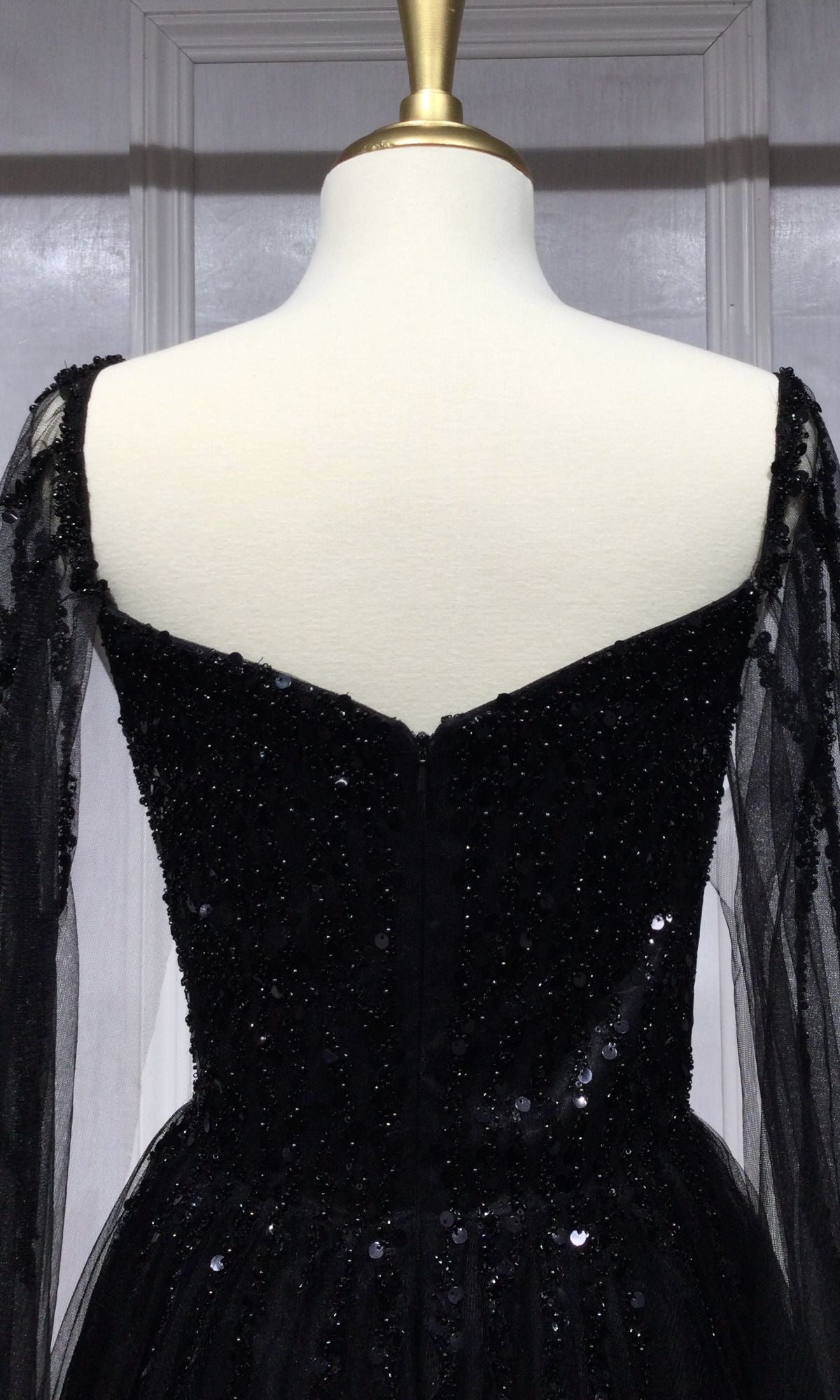 Back view of the Cape-Sleeve Long Beaded Prom Dress CD0204 in black, featuring sheer long sleeves, sequin embellishments, and cape-sleeve detail, displayed on a dress form.
