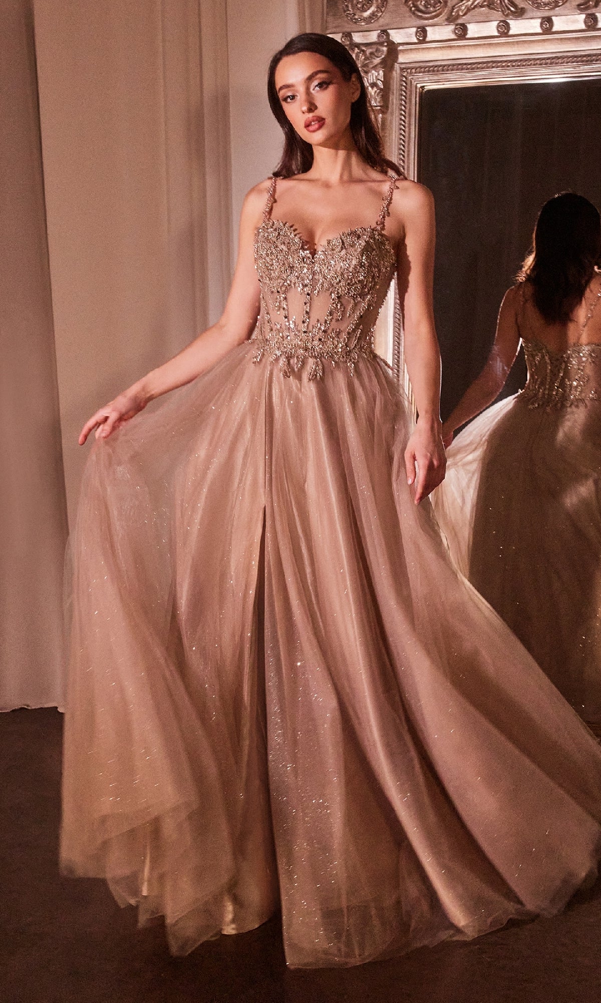 A woman stands before a large ornate mirror wearing the Glitter-Tulle Long Prom Dress: Ladivine CD0234, a shimmering floor-length gown with an embellished sweetheart bodice and intricate beading.
