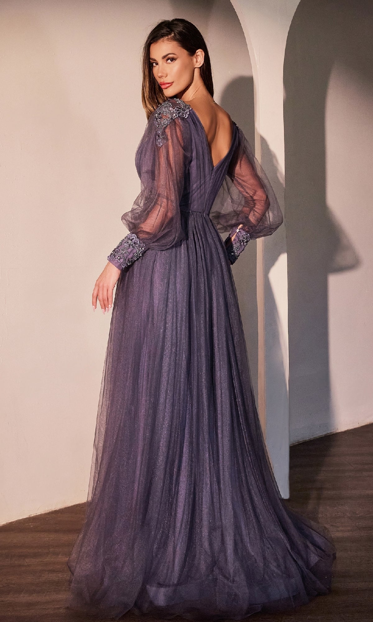 A woman stands indoors wearing the Ladivine CD0938, a long sleeve violet formal dress, looking over her shoulder.