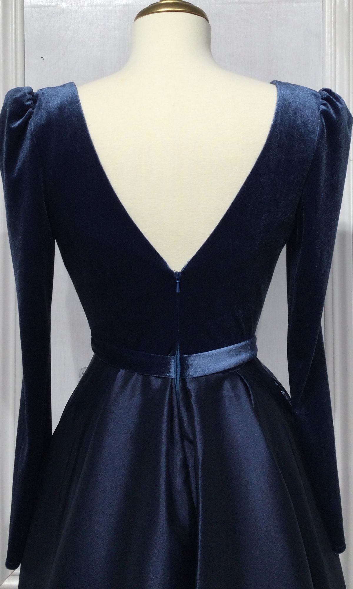 A mannequin displays the Long Sleeve Long A-Line Formal Dress: CD226 in deep blue velvet, featuring a V-shaped open back, fitted waistband, and elegant bodice—ideal as an evening gown.